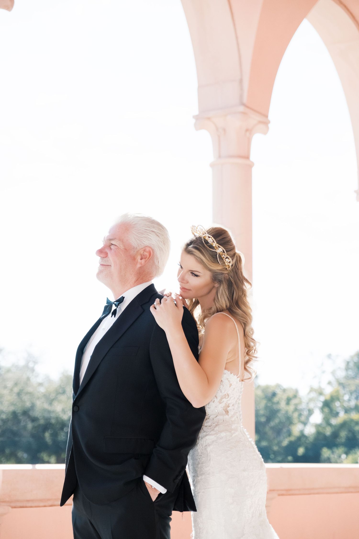 A wedding couple poses on an elegant white stone staircase with ornate balustrades at a historic venue. UK wedding photographer.