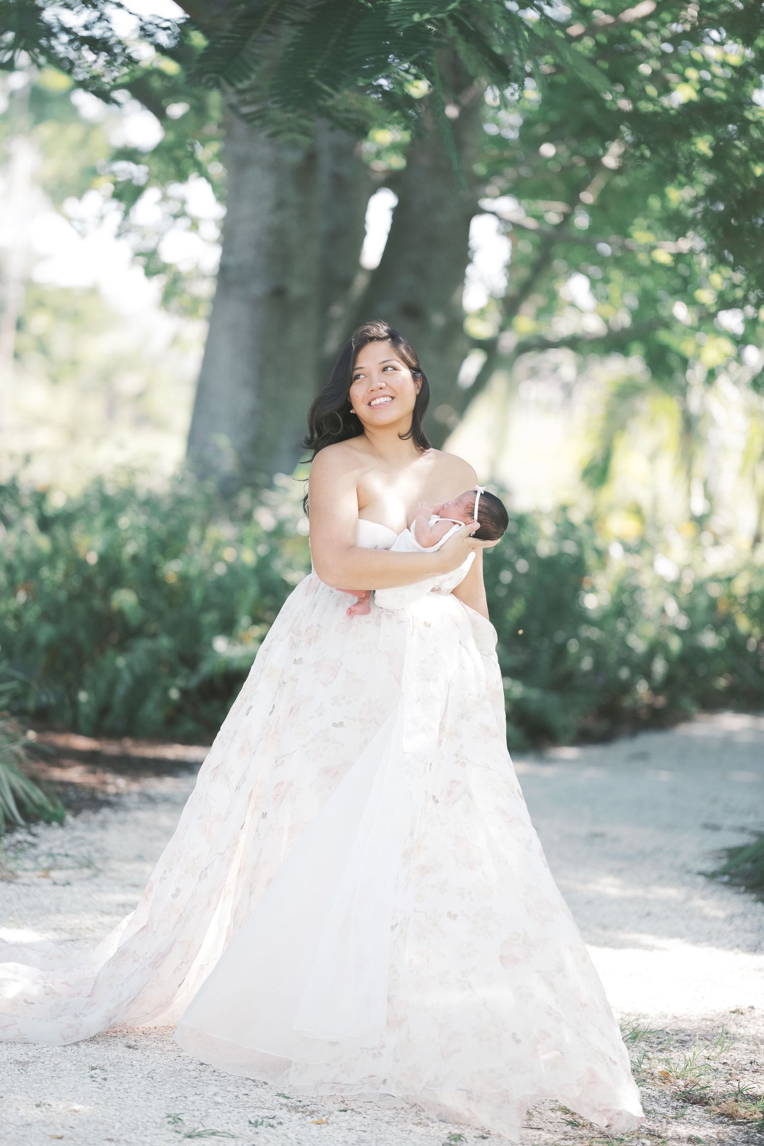 A dreamy portrait in a rose garden with soft bokeh lighting and an off-shoulder white lace dress. Maternity london uk photographer.