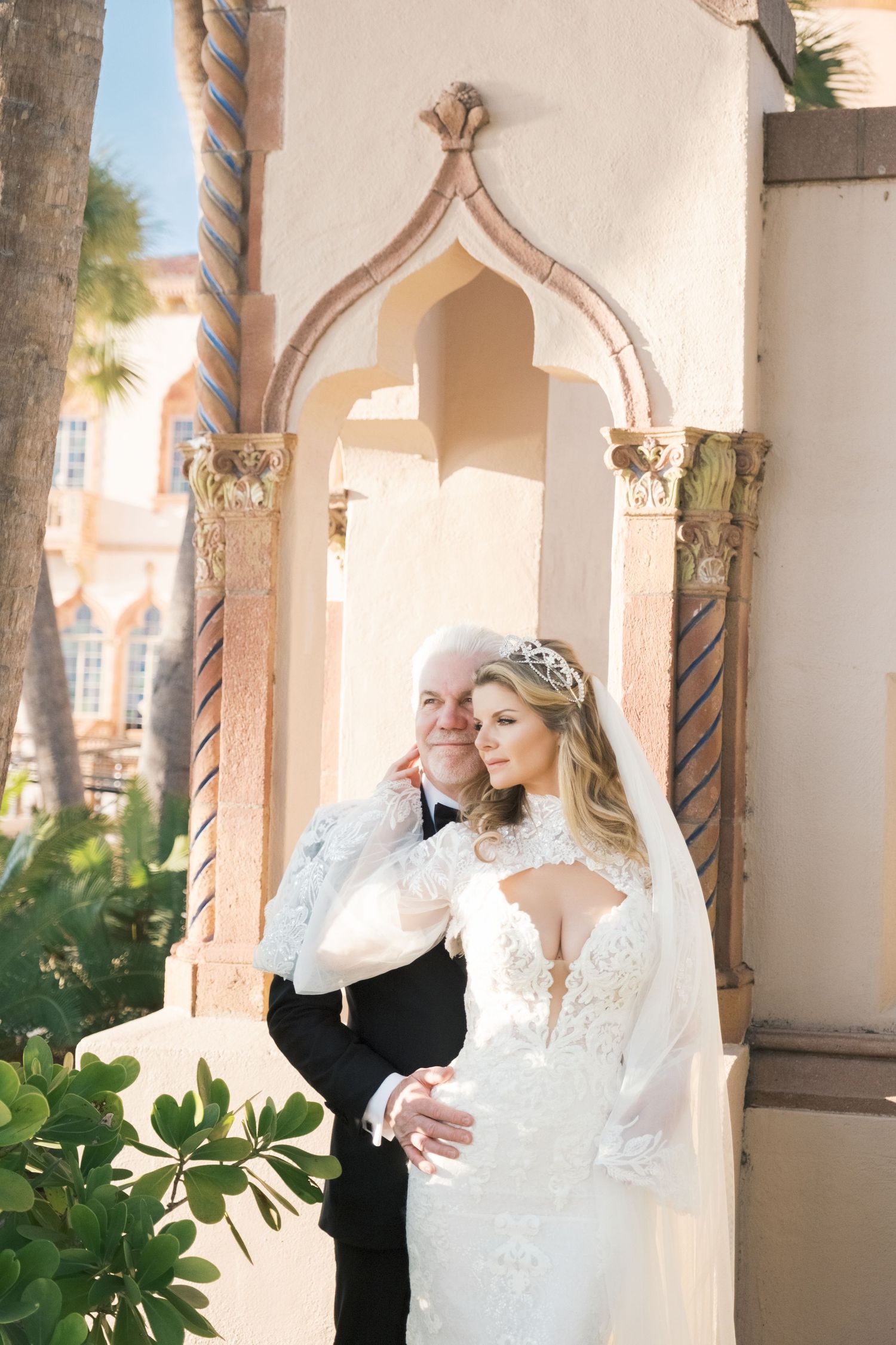 Elegant wedding dress with lace details and flowing sleeves photographed in an archway with ornate columns. london uk wedding photographer.