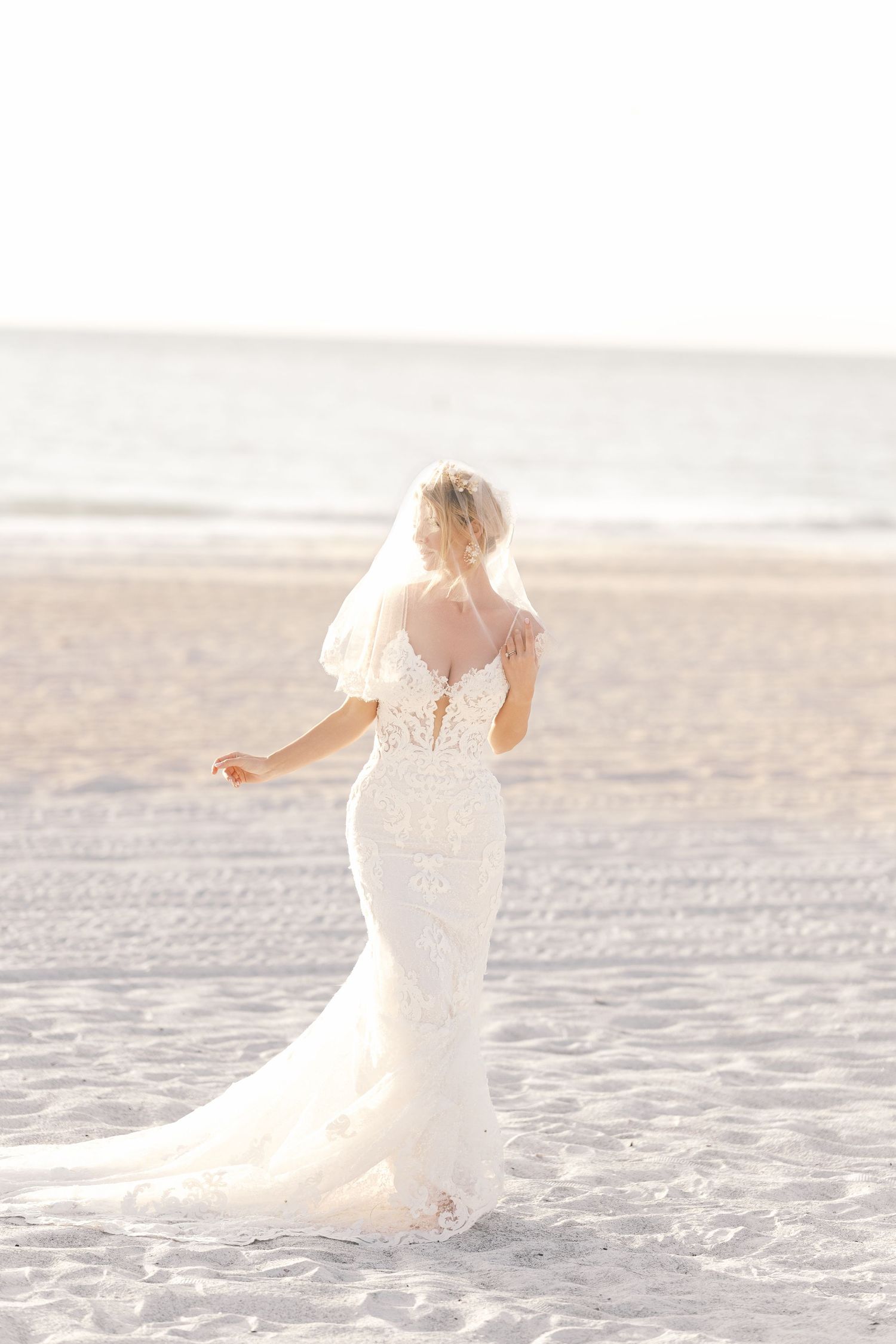 A person in a flowing white dress twirls gracefully on a sunlit beach, creating a dreamy ethereal scene. Wedding uk photographer.
