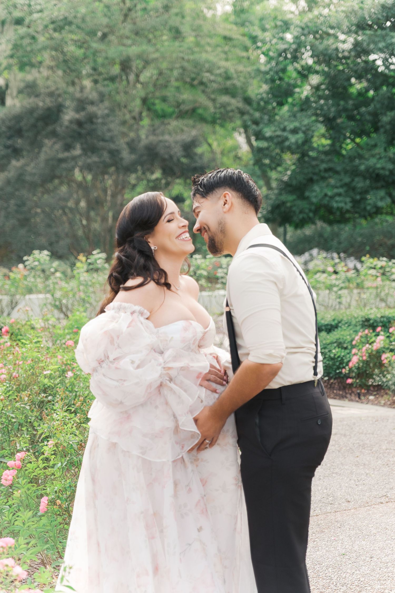 Romantic expecting couple shares tender moments in a lush garden setting surrounded by blooming flowers and greenery. Maternity UK session.