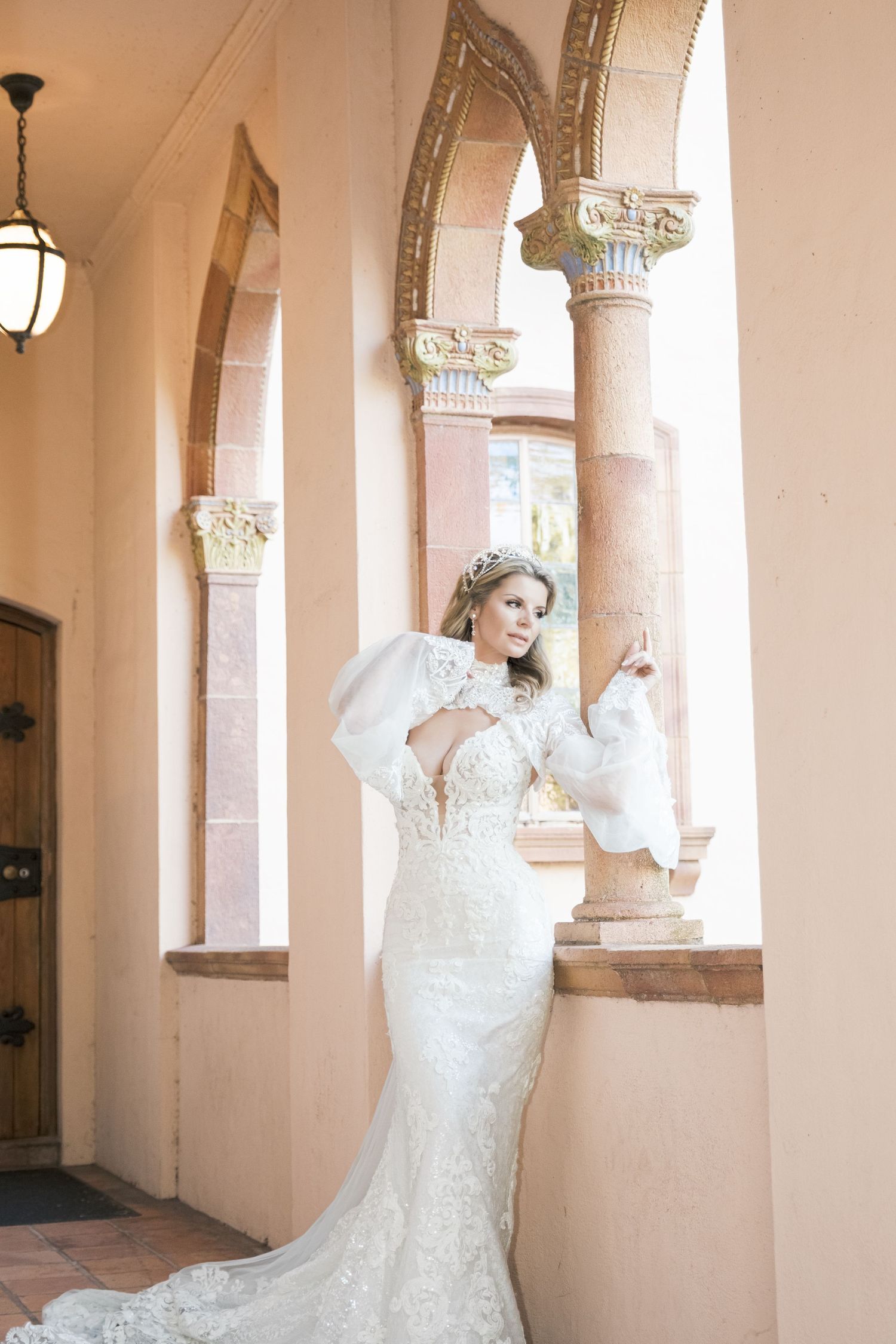 Elegant wedding dress with lace details and flowing sleeves photographed in an archway with ornate columns. london uk wedding photographer.