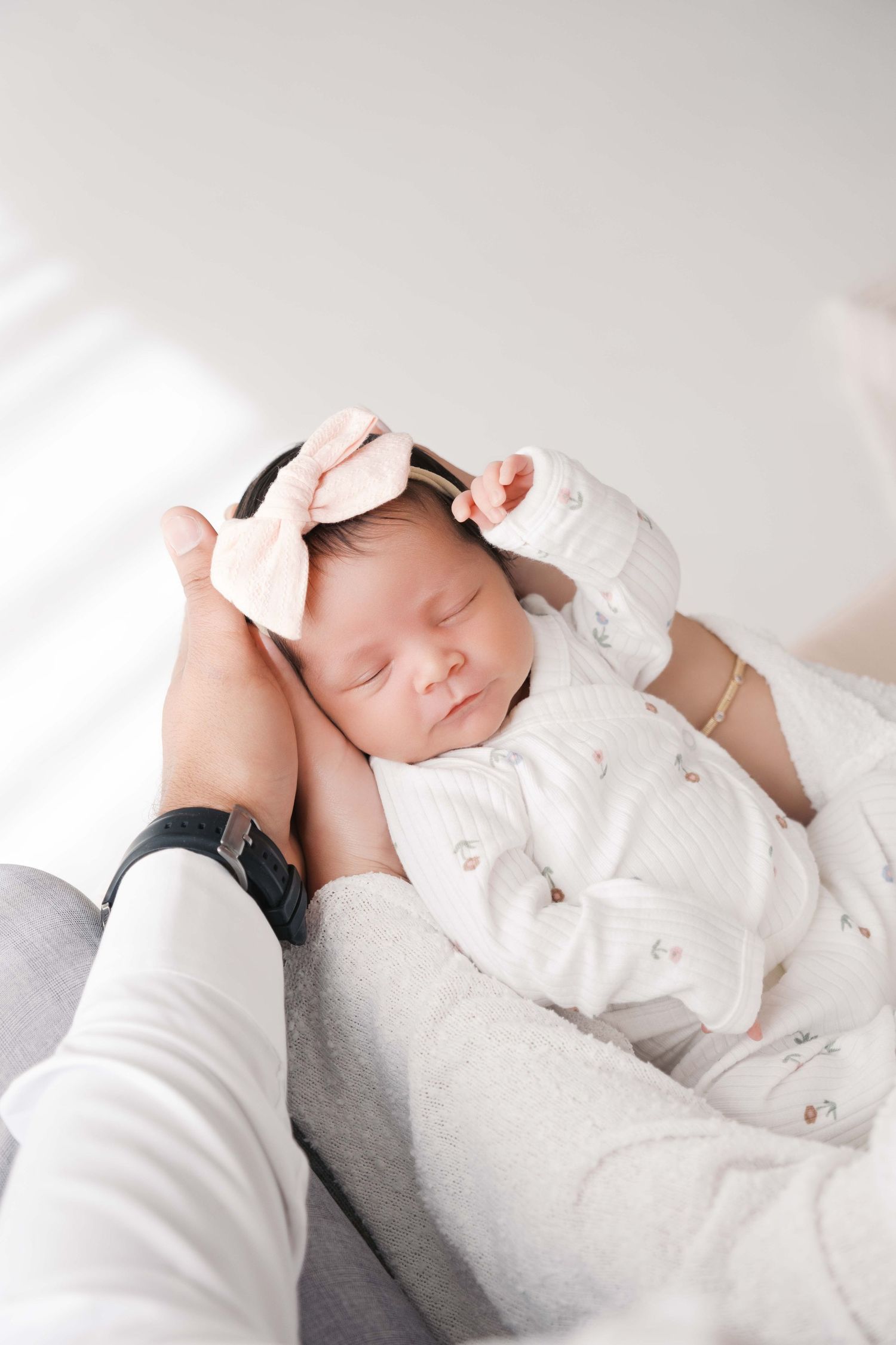 A sleeping newborn baby wrapped in delicate white lace is captured in a series of gentle close-up portraits. london uk