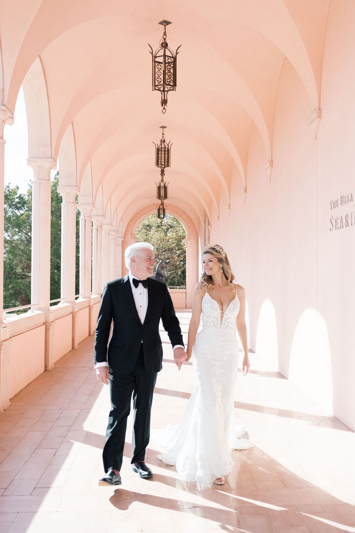 A wedding couple poses on an elegant white stone staircase with ornate balustrades at a historic venue. UK wedding photographer.