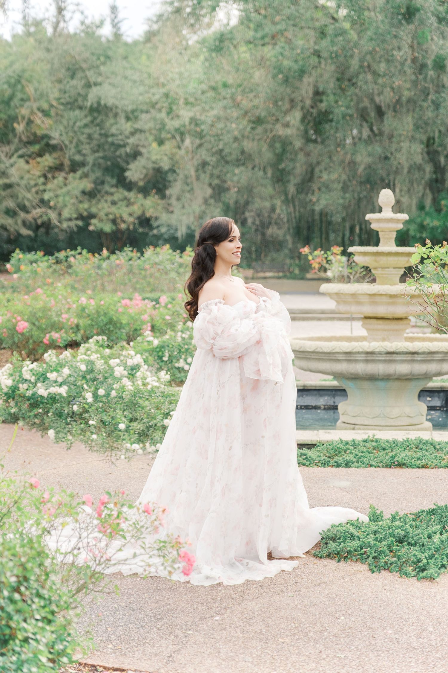 A maternity photo session in a garden gazebo featuring a flowing pink dress and lush greenery background. london uk maternity photographer