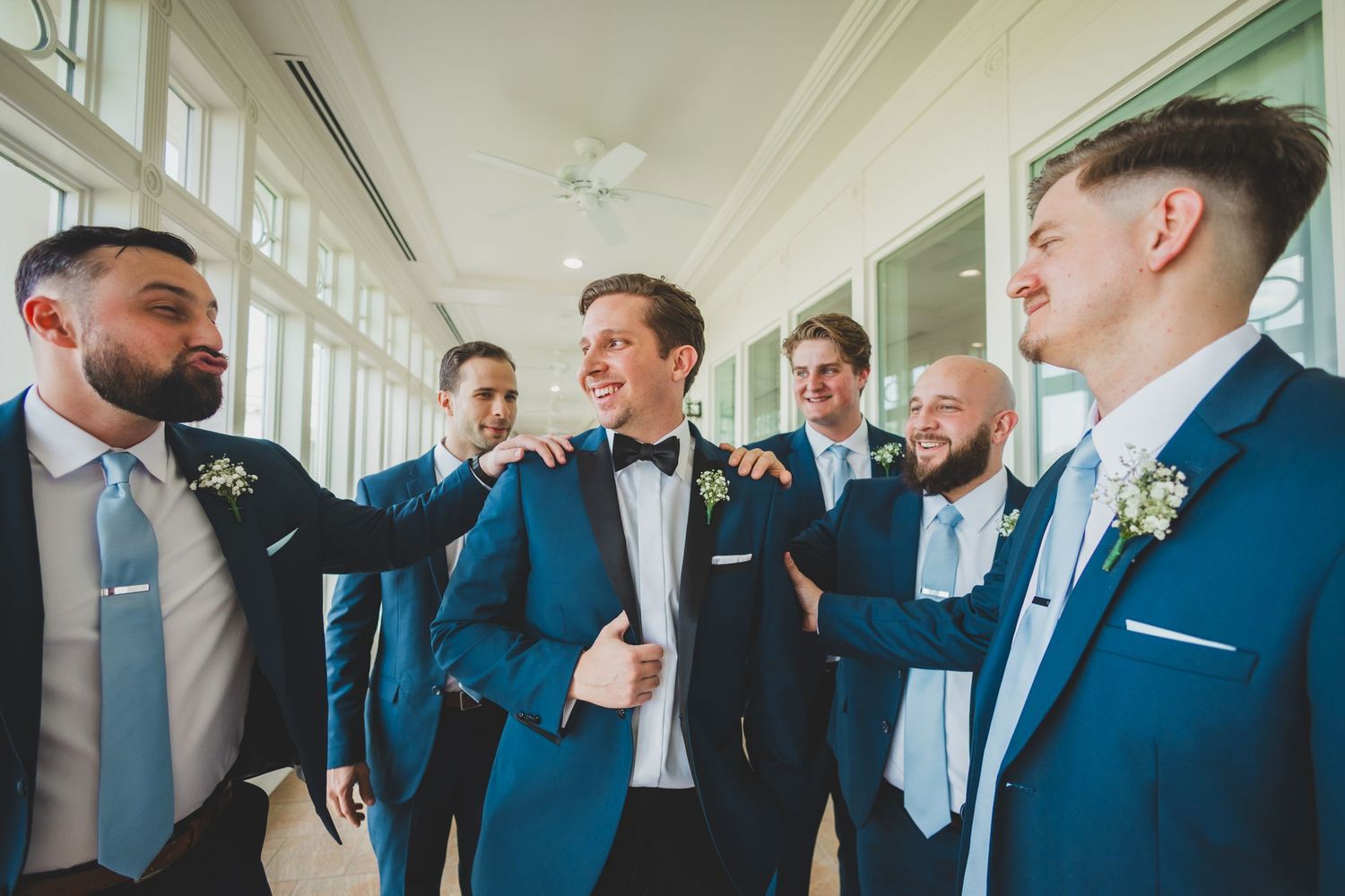 Groomsmen in blue suits sharing a laugh together before the wedding ceremony.