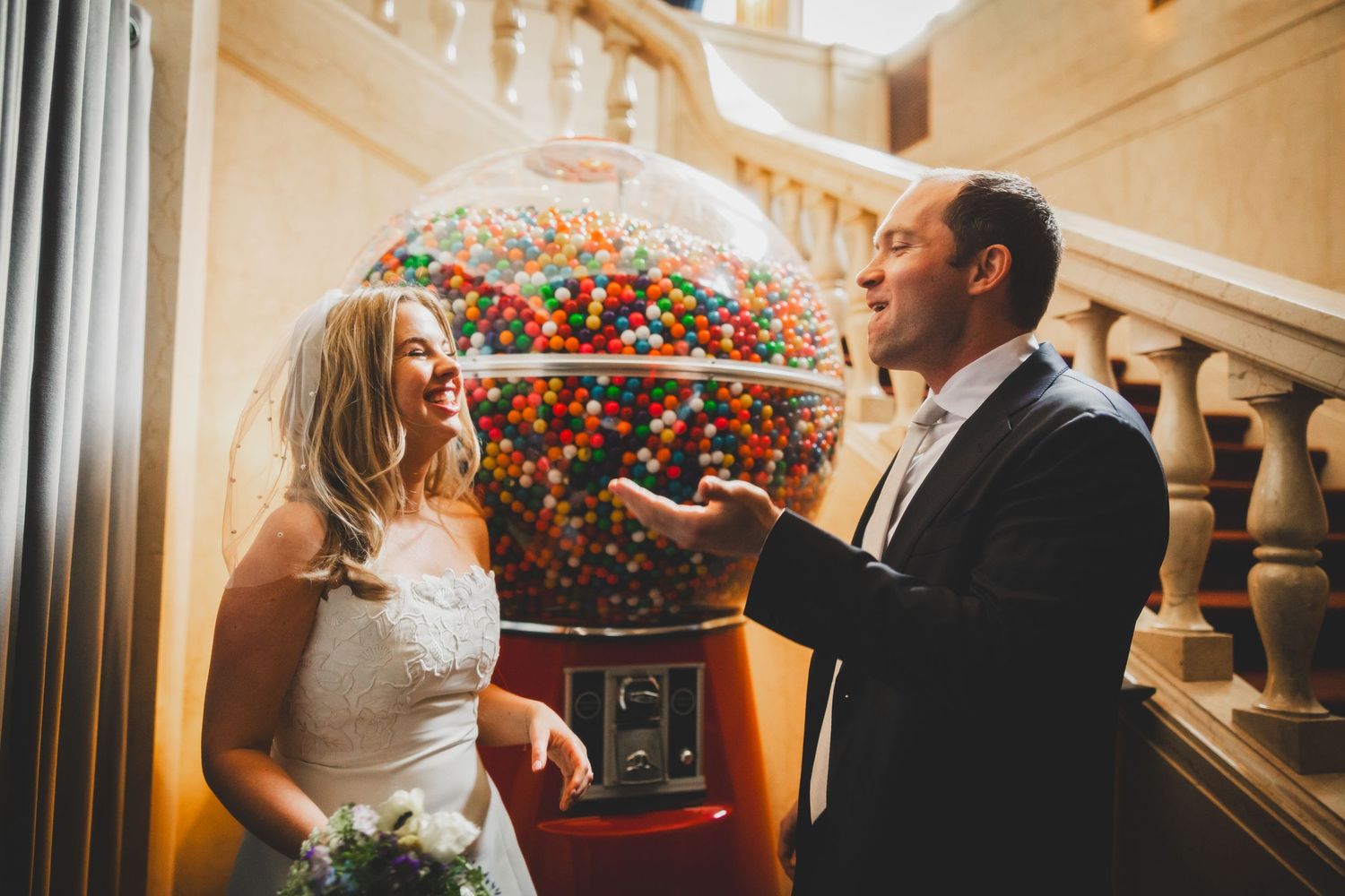 Wedding couple admires an ornate glass globe while posing on elegant staircase.