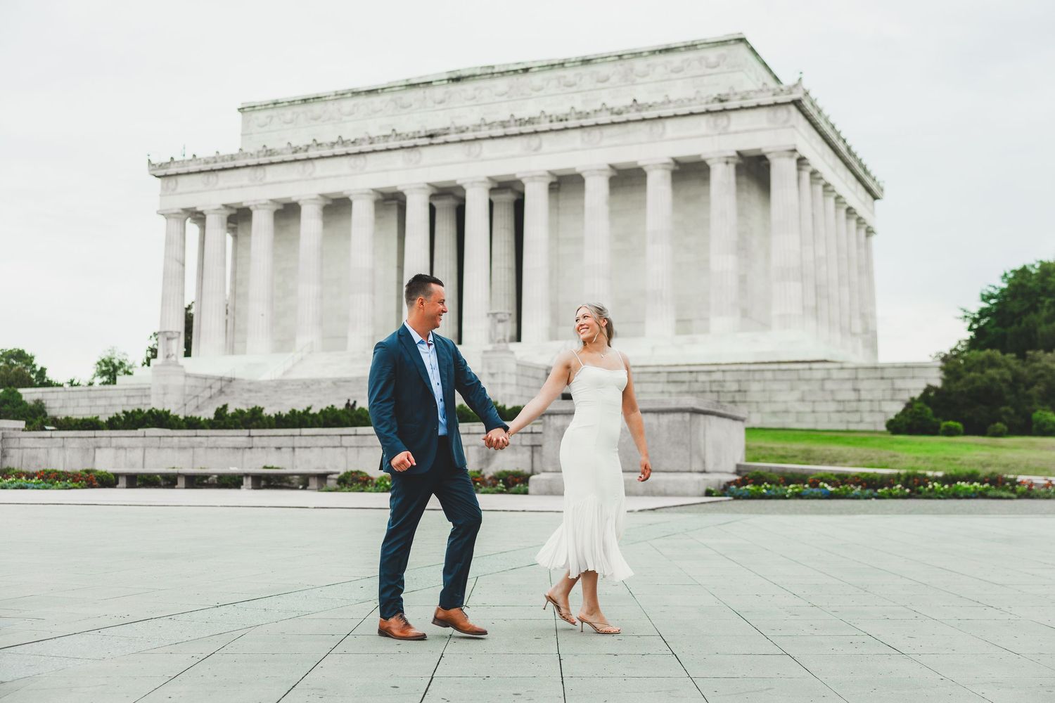 Couple holding hands walking in front of the Lincoln Memorial in Washington DC on their wedding day.