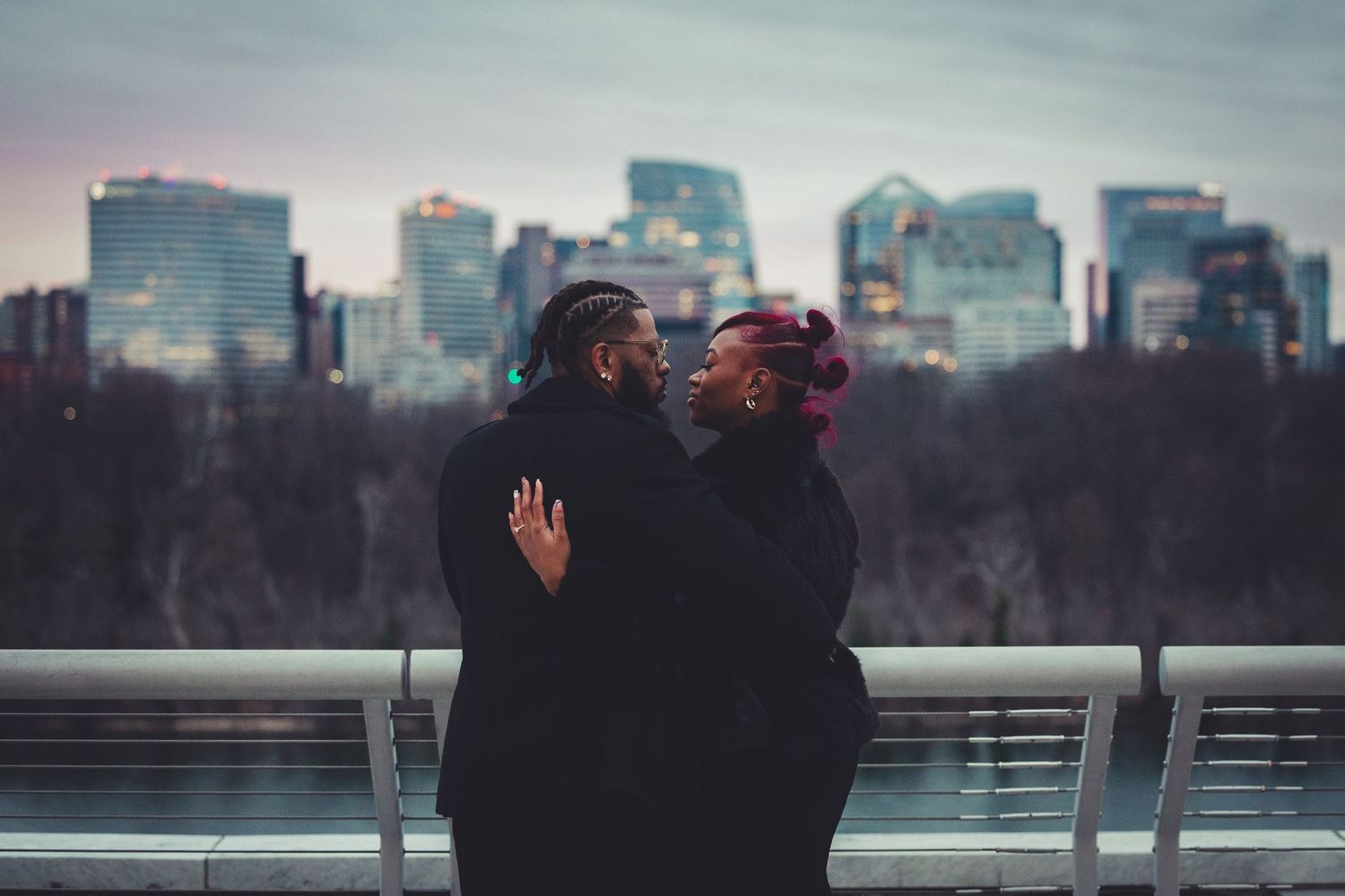 cinematic portrait of engaged couple looking at the sunset over a cityscape