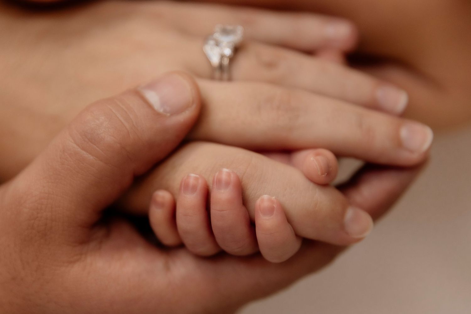 Newborn baby's hand resting in a parent's hand, close-up detail