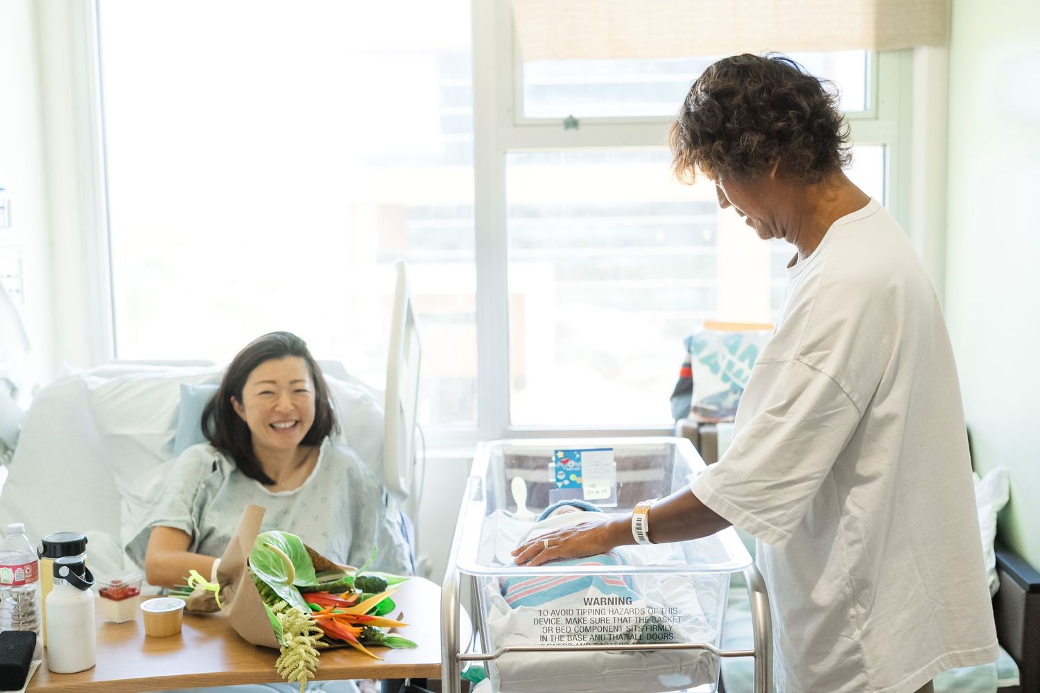 Two people prepare a meal together in a bright kitchen while sharing a cheerful moment near a window. Oahu Fresh48