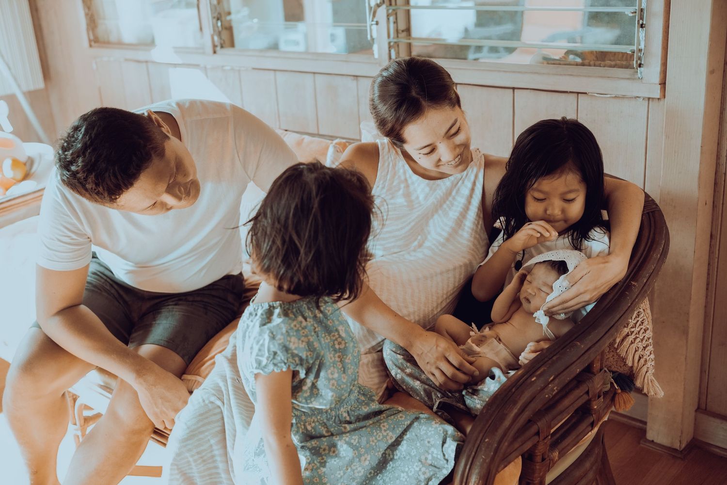 A family spending time together in a casual home setting with natural lighting and warm tones. Oahu Newborn Photographer
