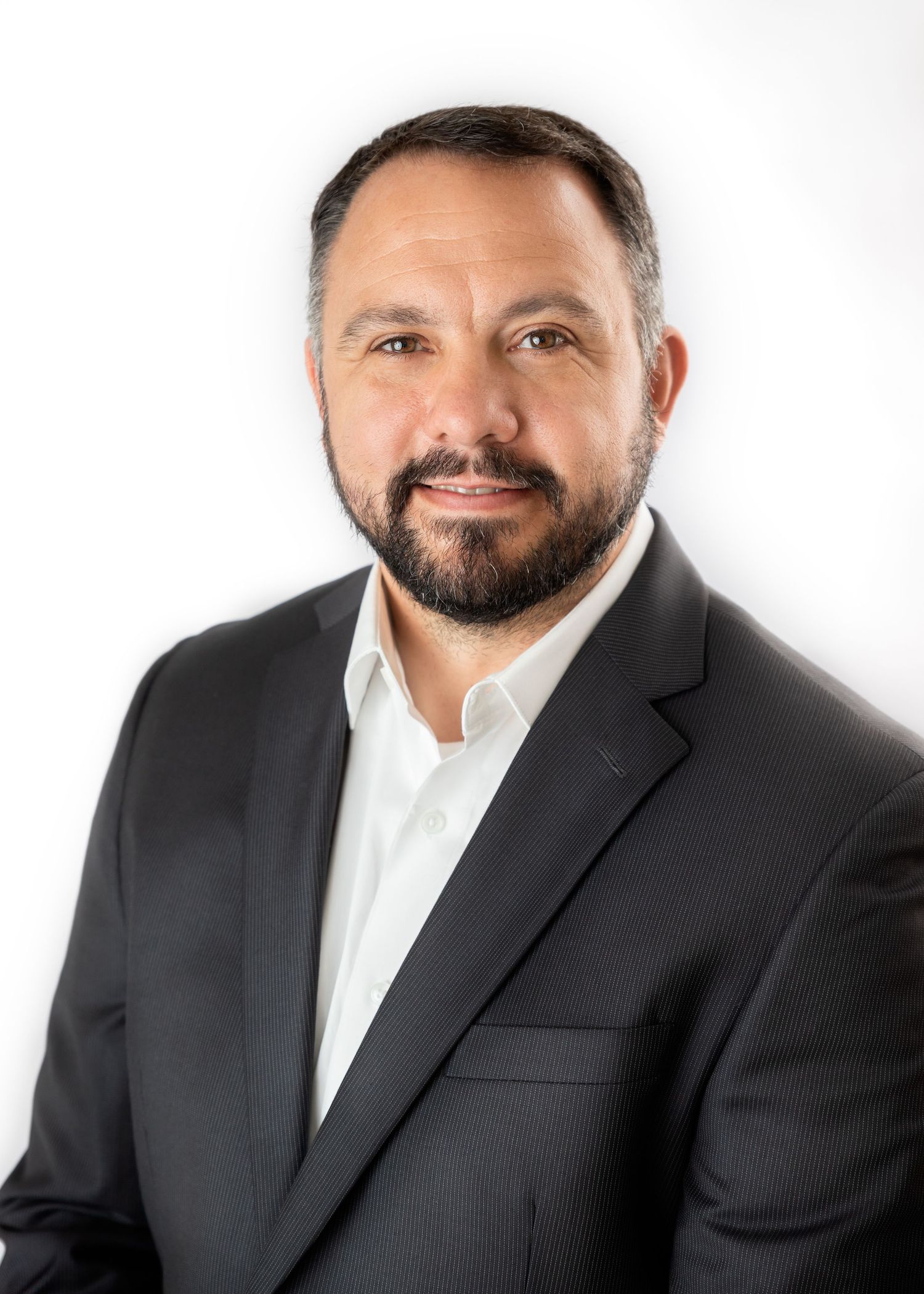 Professional studio portrait of someone wearing a black suit and white shirt against a white background.
