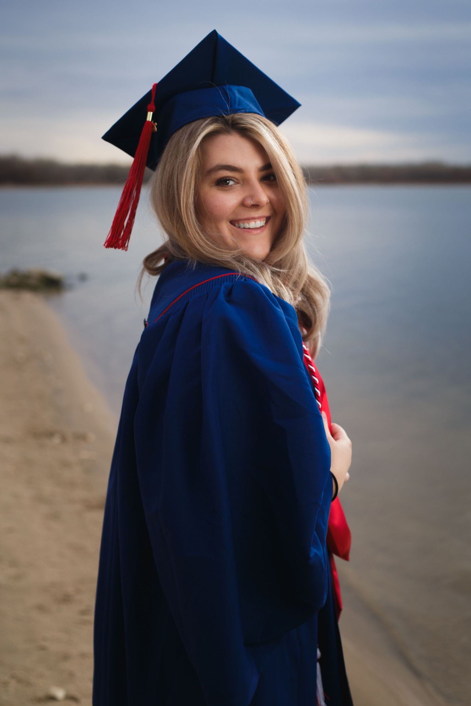 Senior graduation portrait at the beach — woman in blue cap and gown with red tassel, Littleton, CO senior photography by Graham Tipton.