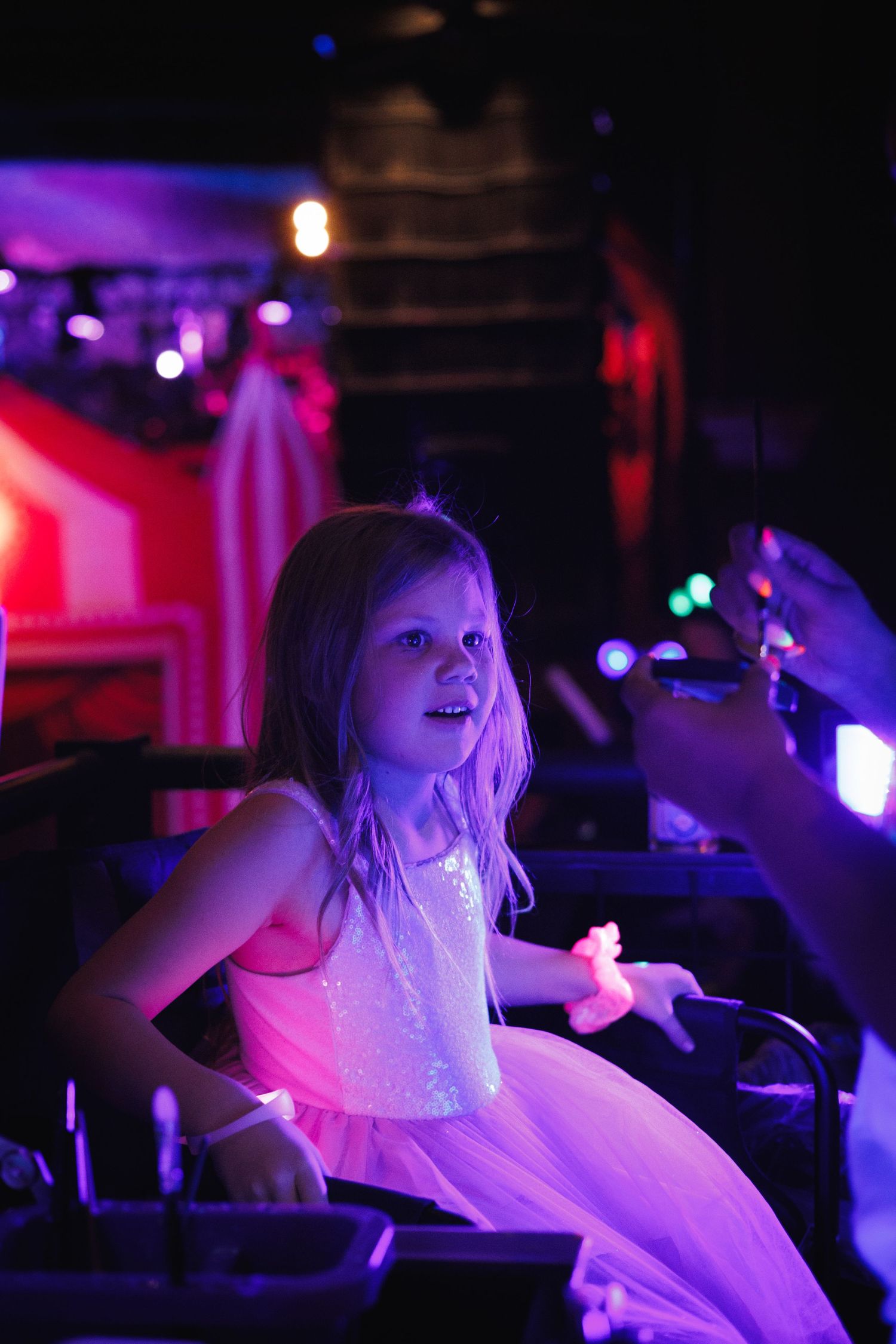Birthday party event photography — guest seated in moody purple stage lighting, Littleton, CO event photographer Graham Tipton.