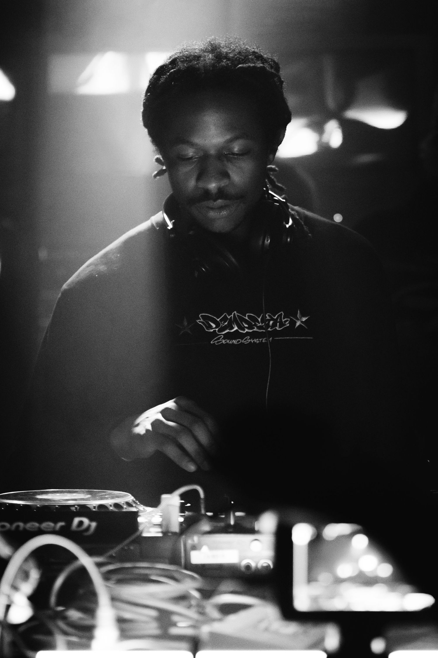 Black and white event photography — performer working at music equipment at a Moonlight Collective show, Littleton, CO by Graham Tipton.
