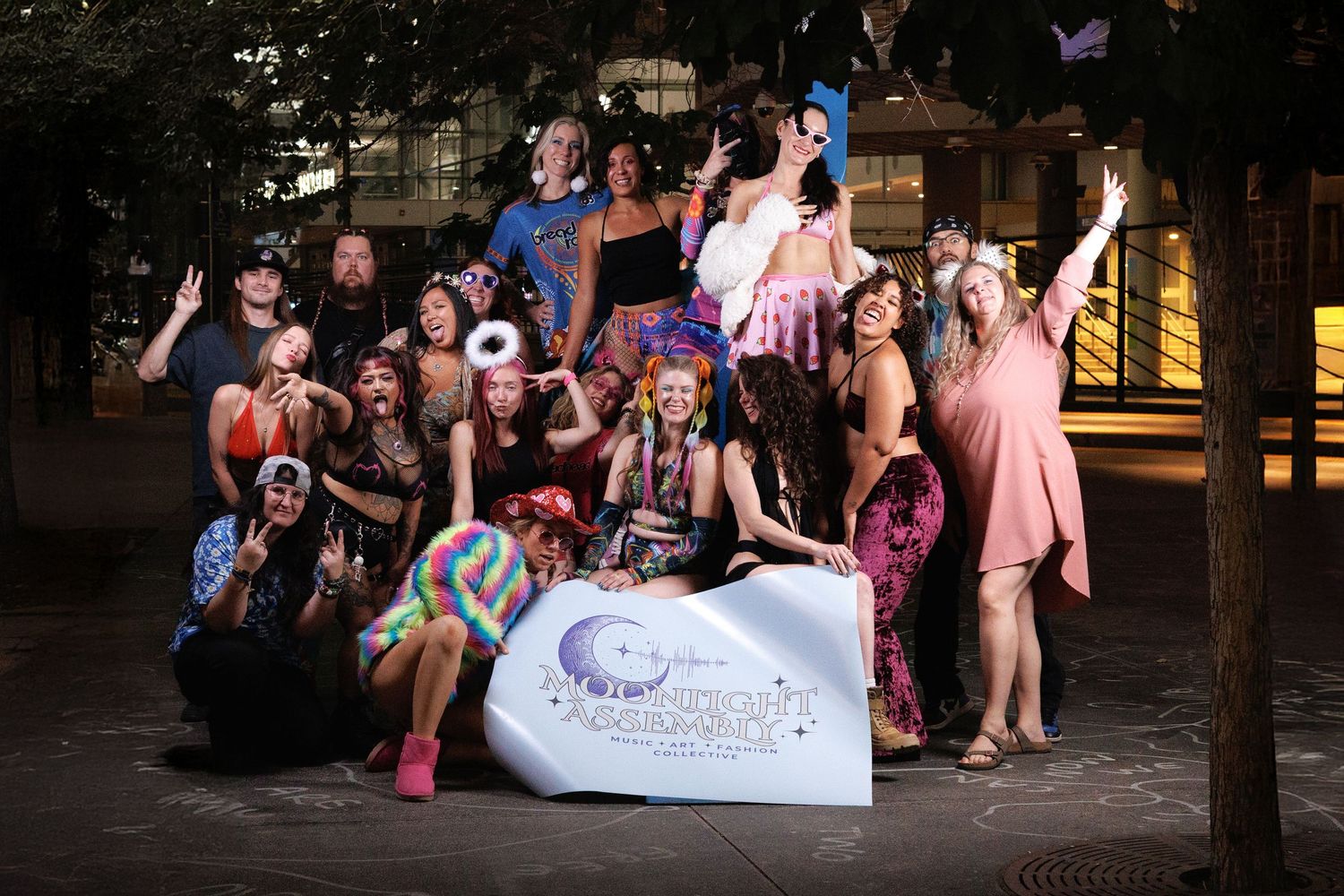 Littleton event photography — group of performers posing with a Moonlight Collective banner at night.