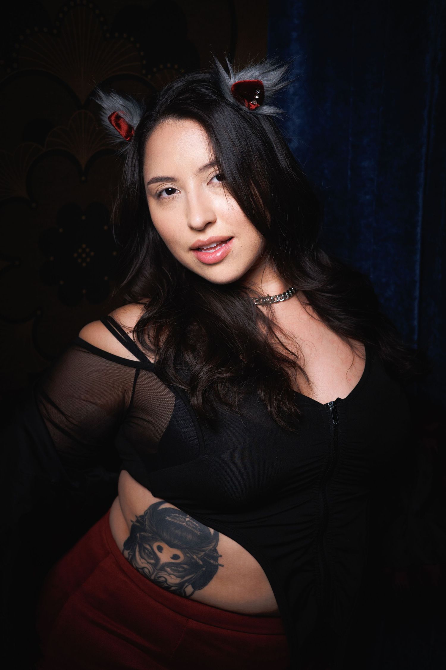 Gothic-themed creative portrait — woman with black cat ears and dark hair against deep red backdrop, editorial photography in Littleton, CO.