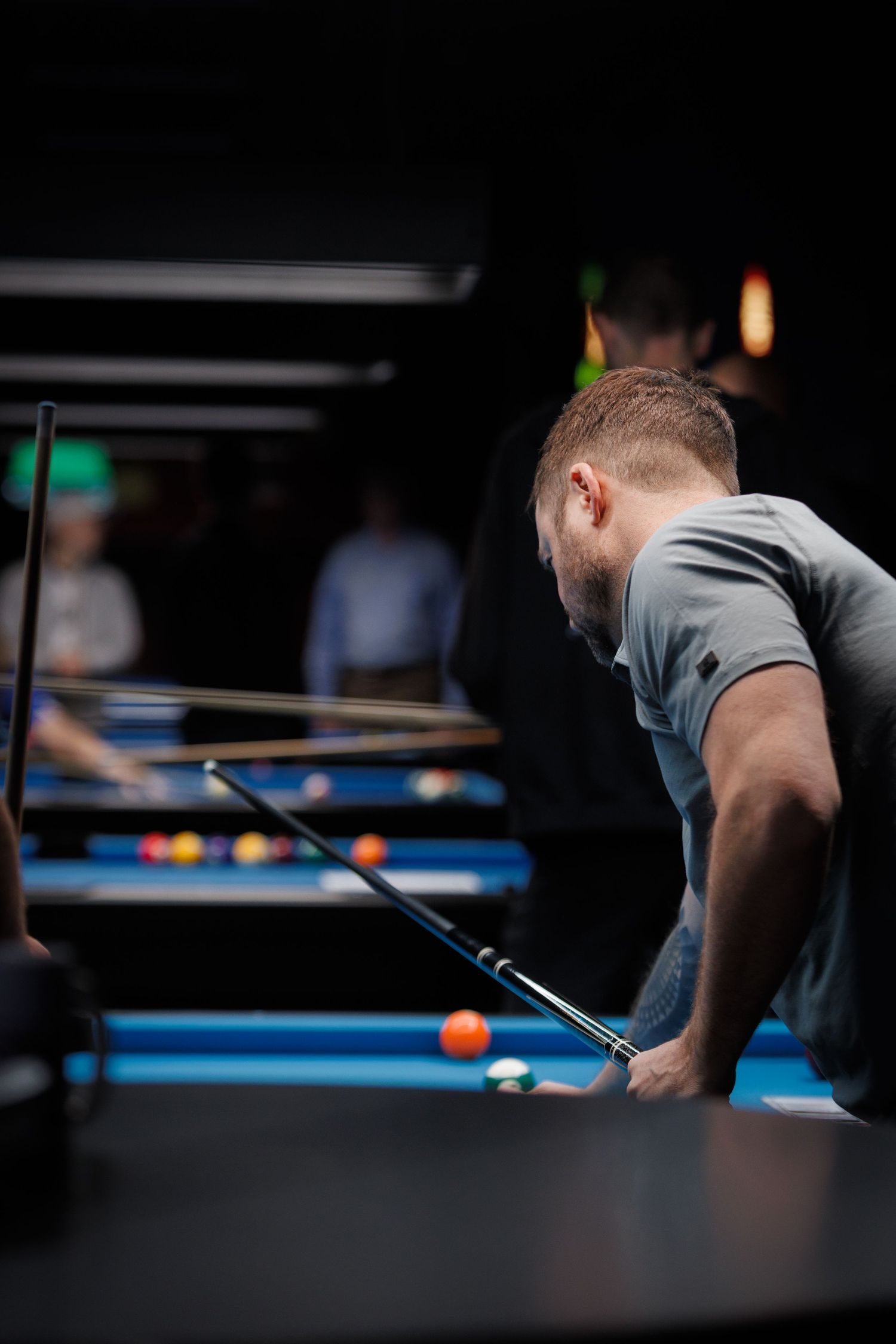 Birthday party event photography — guest playing pool at a billiards table in dim, moody lighting, Littleton, CO by Graham Tipton.