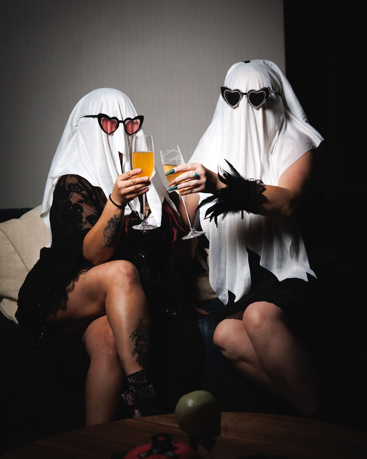 Halloween themed creative portrait — two friends in ghost sheet costumes posing with drinks, editorial photography in Littleton, CO.