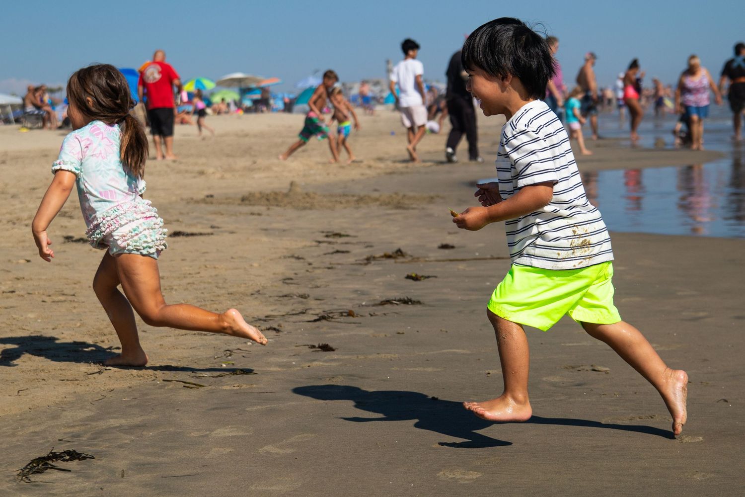 toddler girl and boy running on the beach