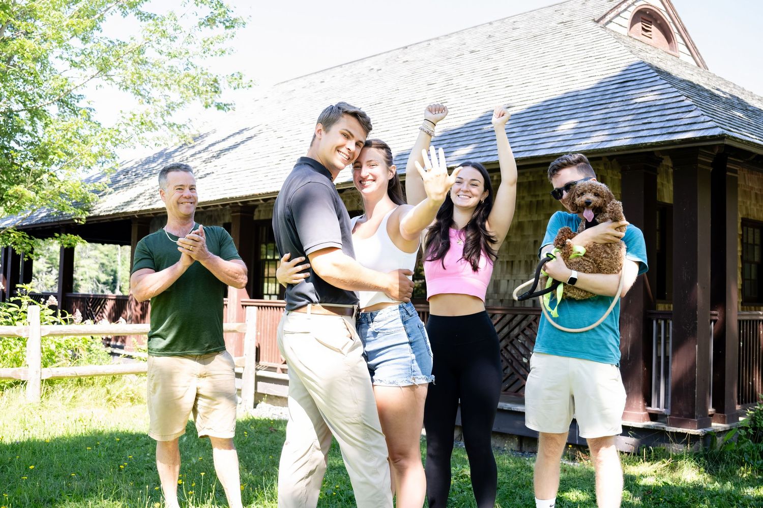 Group of people dancing and socializing at an outdoor summer gathering near a rustic building.