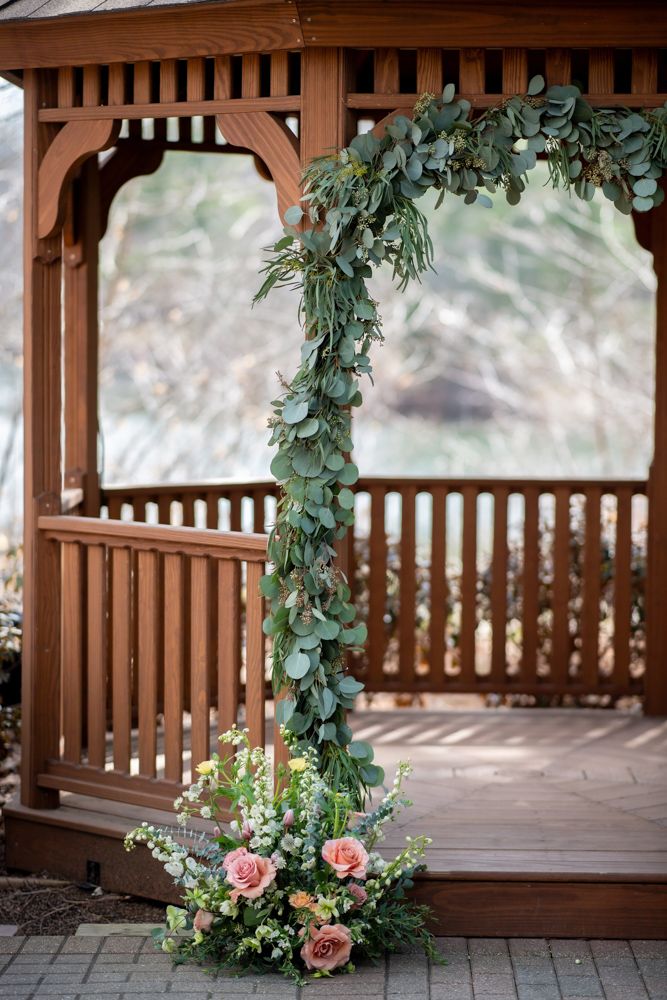 Wedding ceremony arch with pink and red roses by Fountain Head Floral Design at the Pavilion on Crystal Lake.