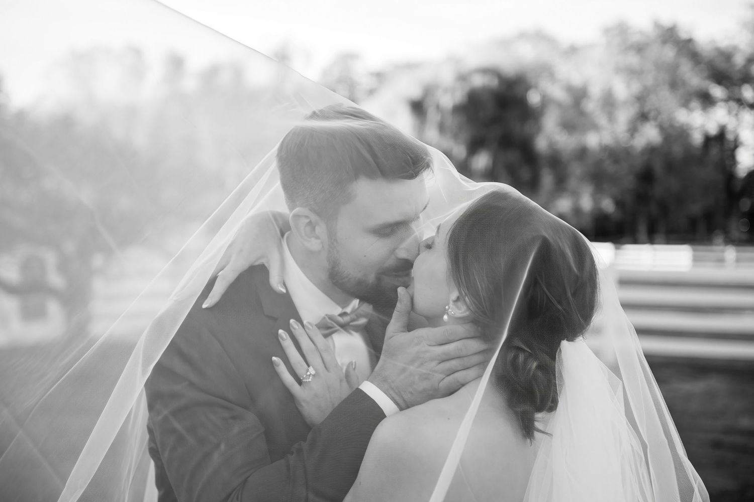 Black and white wedding photo of bride and groom sharing intimate moment under veil.
