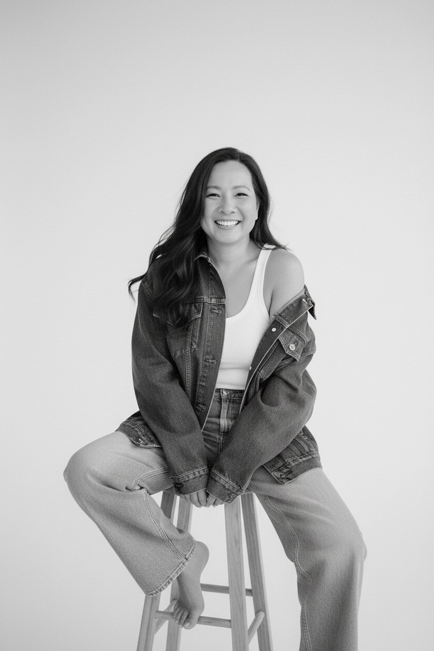 A black and white photo series showing someone sitting casually on a stool in a denim jacket and pants.