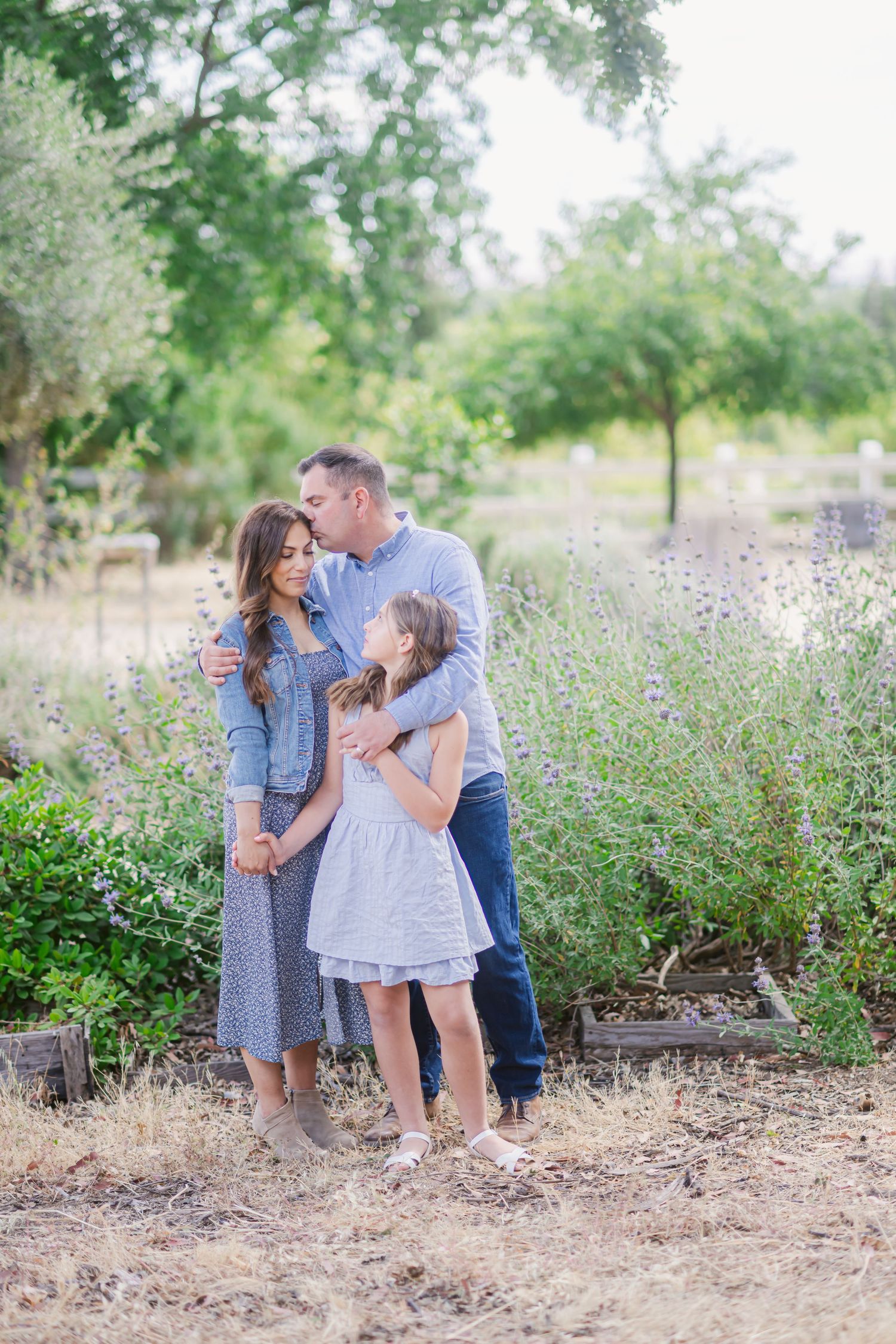 Family shares tender moments together in a wildflower field during outdoor photo session at golden hour.
