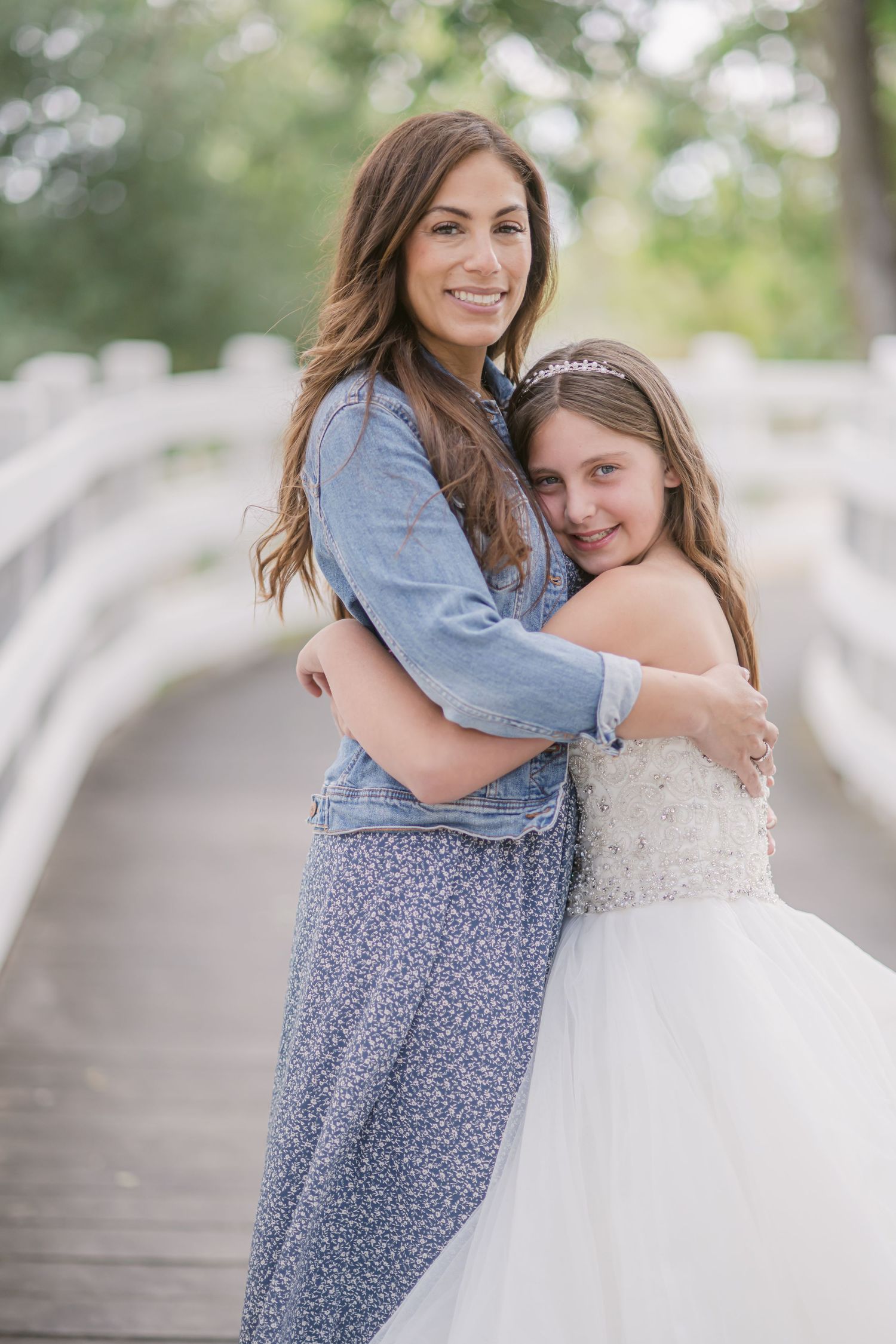 Two people share a tender hug outdoors in coordinating blue outfits with soft natural lighting and bokeh effect.