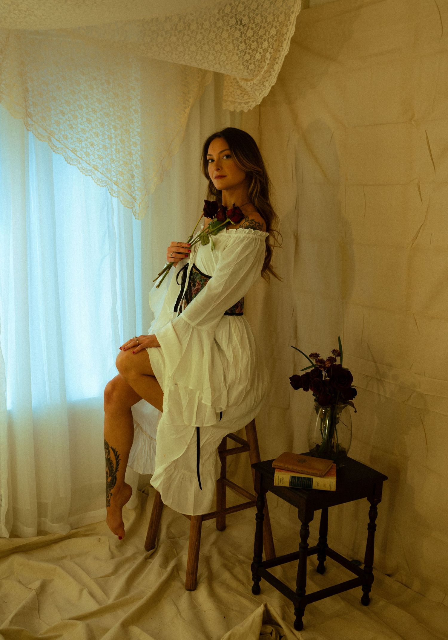 Artistic portrait in a sunlit room with lace curtains and vintage furniture.