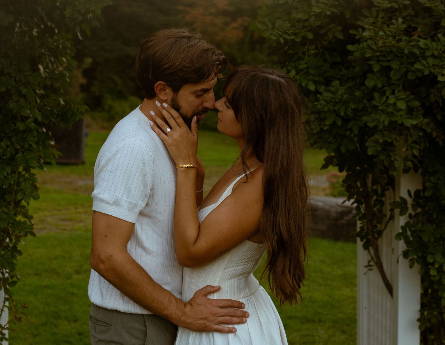 A romantic sequence showing a couple in white clothing embracing in a lush garden setting.