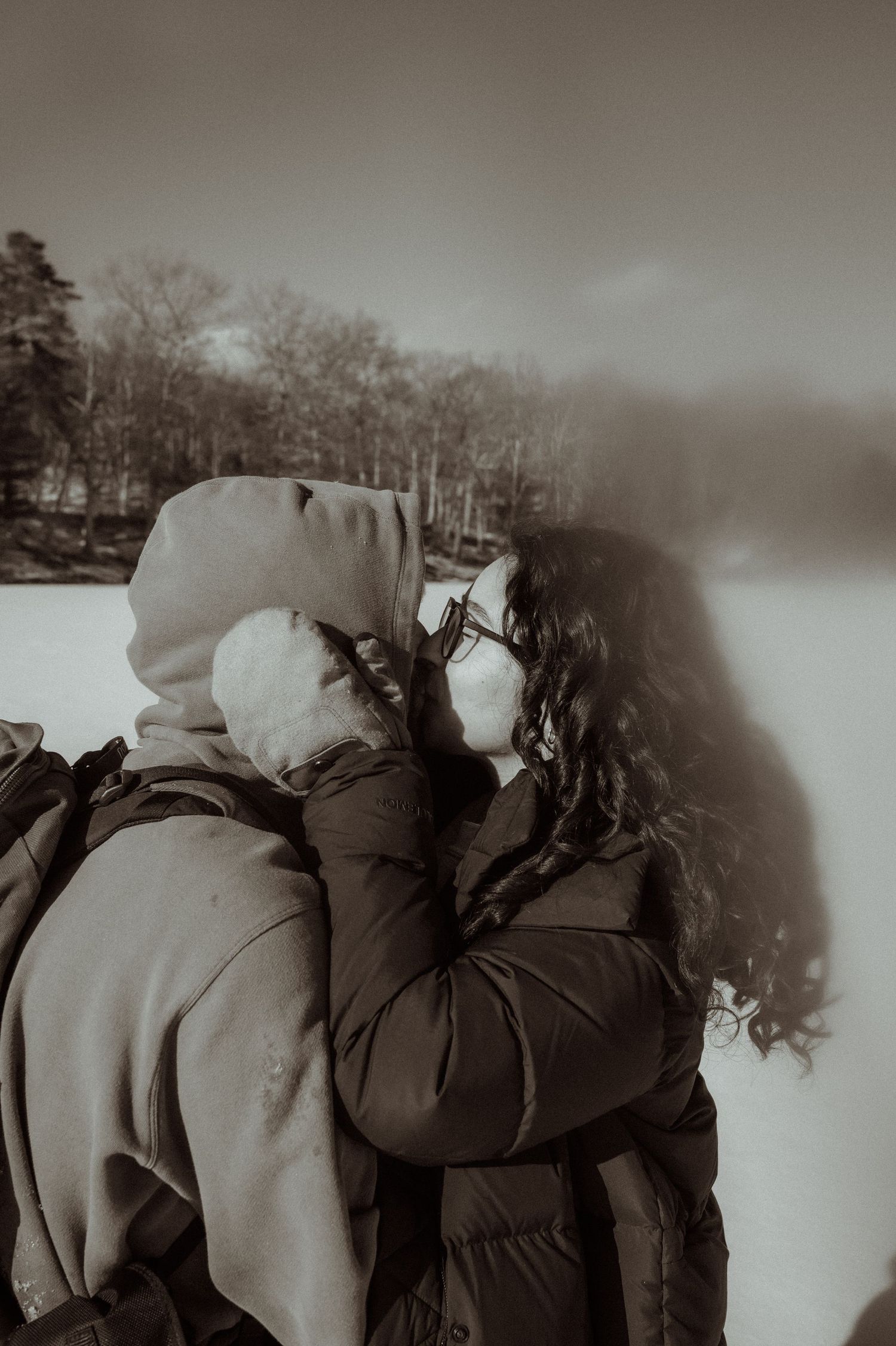 Winter portrait of a couple in warm coats sharing an intimate moment against a snowy backdrop.