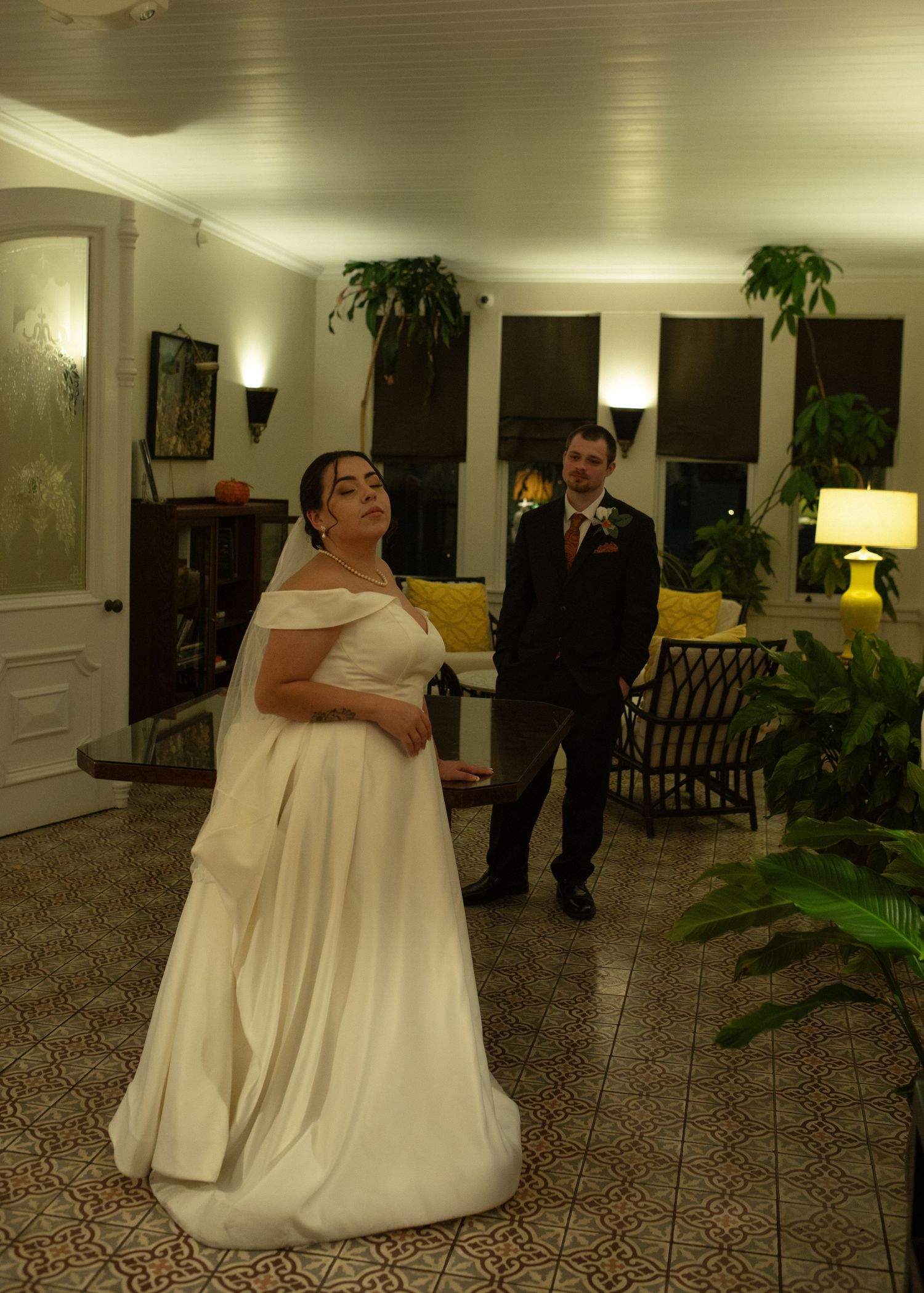 A wedding celebration in an elegant living room with indoor plants, yellow accents and patterned carpet.