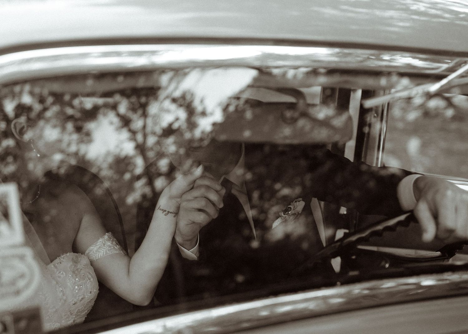 A sepia-toned photo taken through a car window during a wedding.