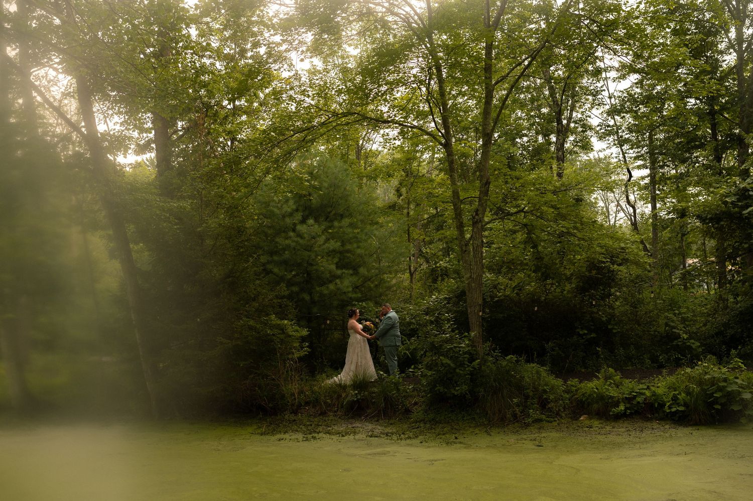 A romantic outdoor wedding ceremony setup with chairs in a wooded area at sunset.