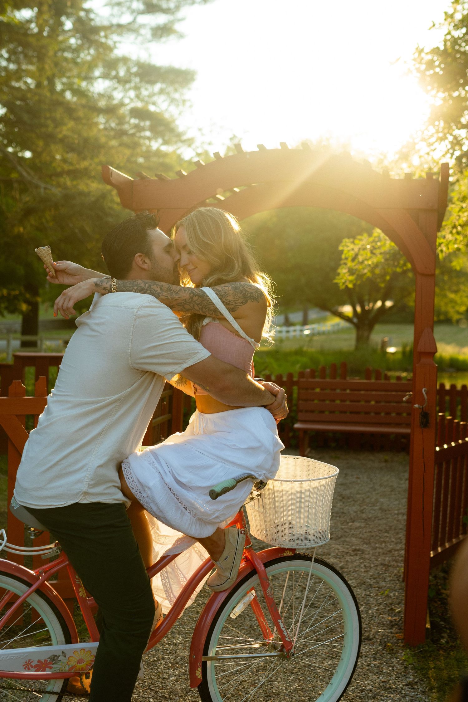 A playful couple riding together on a vintage bicycle during sunset in a park.