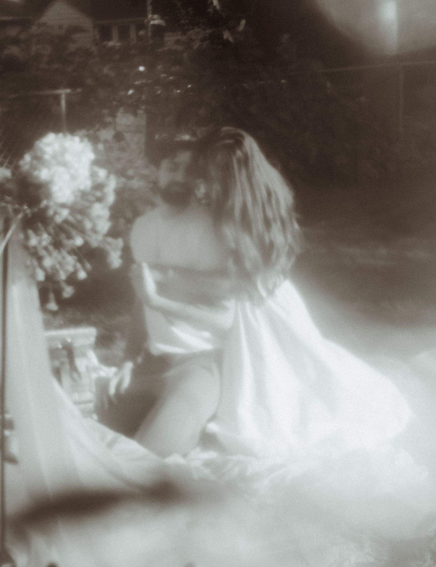 Dreamy black and white photograph of a bride with flowers creating an ethereal effect.