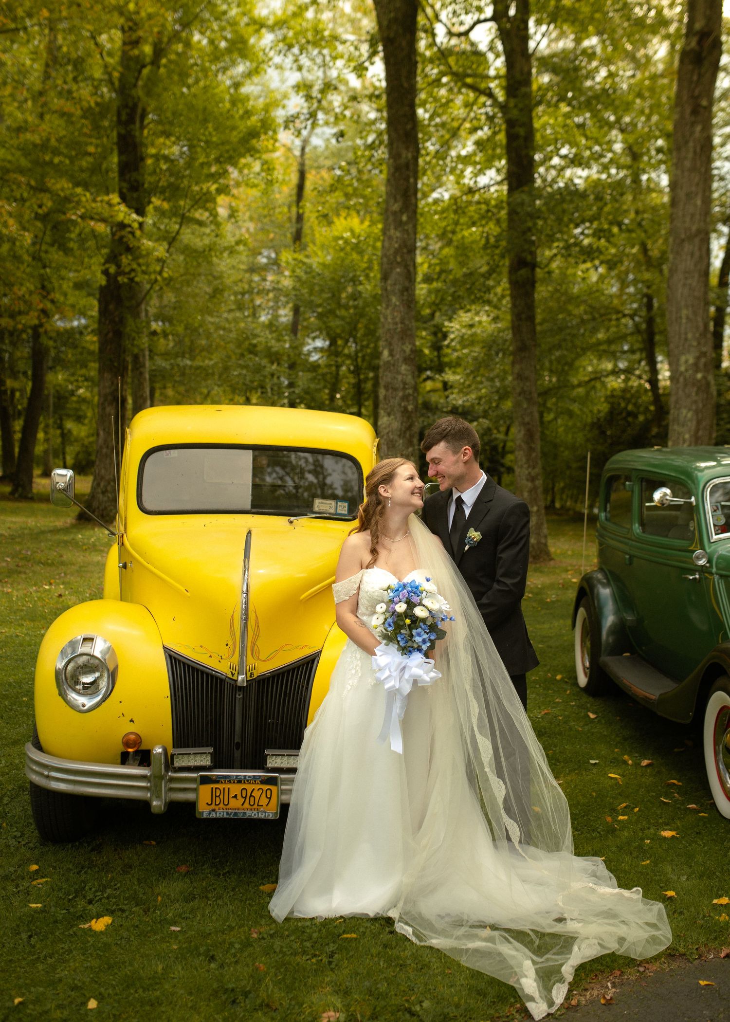 A classic yellow vintage car parked in a forest setting during a wedding photoshoot.