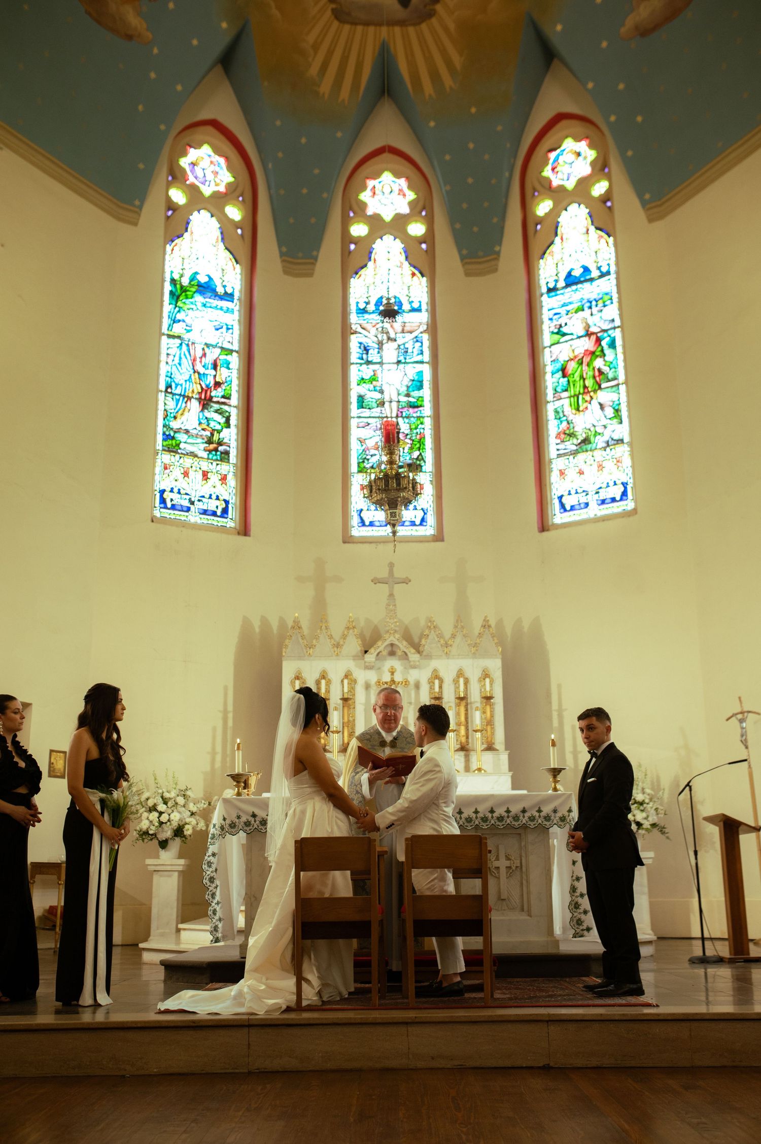 Wedding ceremony in a church with beautiful stained glass windows and traditional altar.