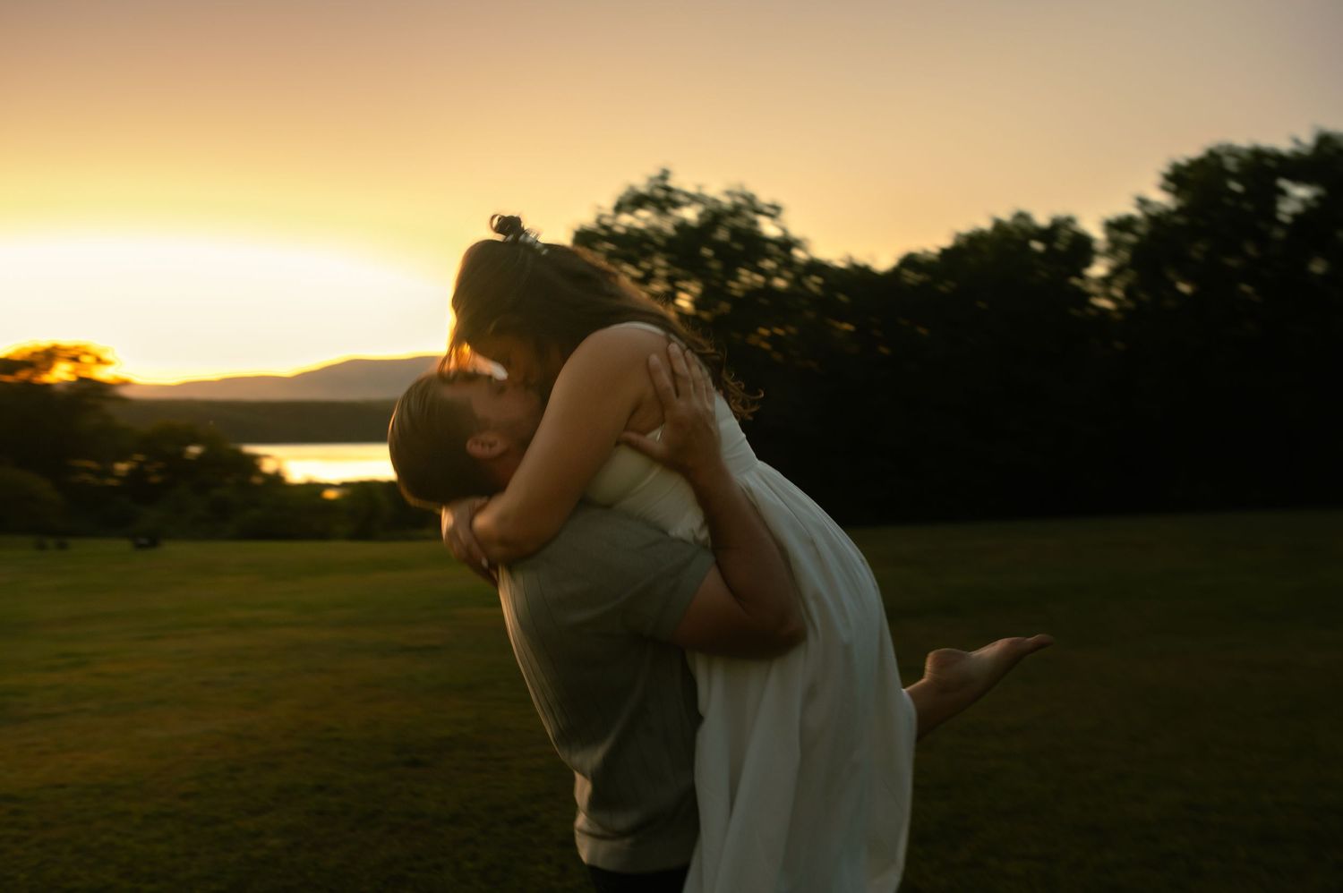 Silhouettes of two people embracing against a golden sunset sky.