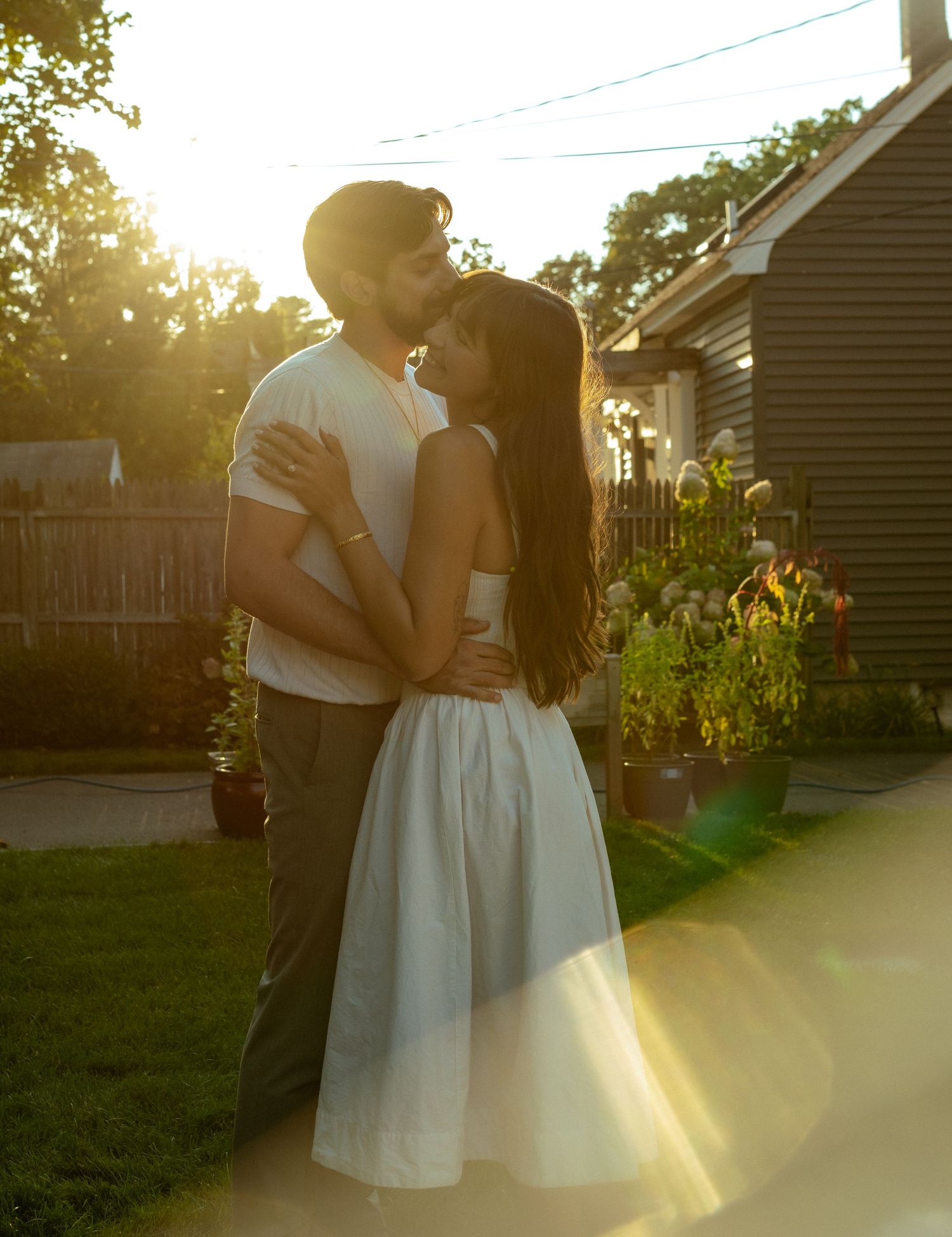 A romantic sunset embrace in a backyard garden with golden light filtering through.