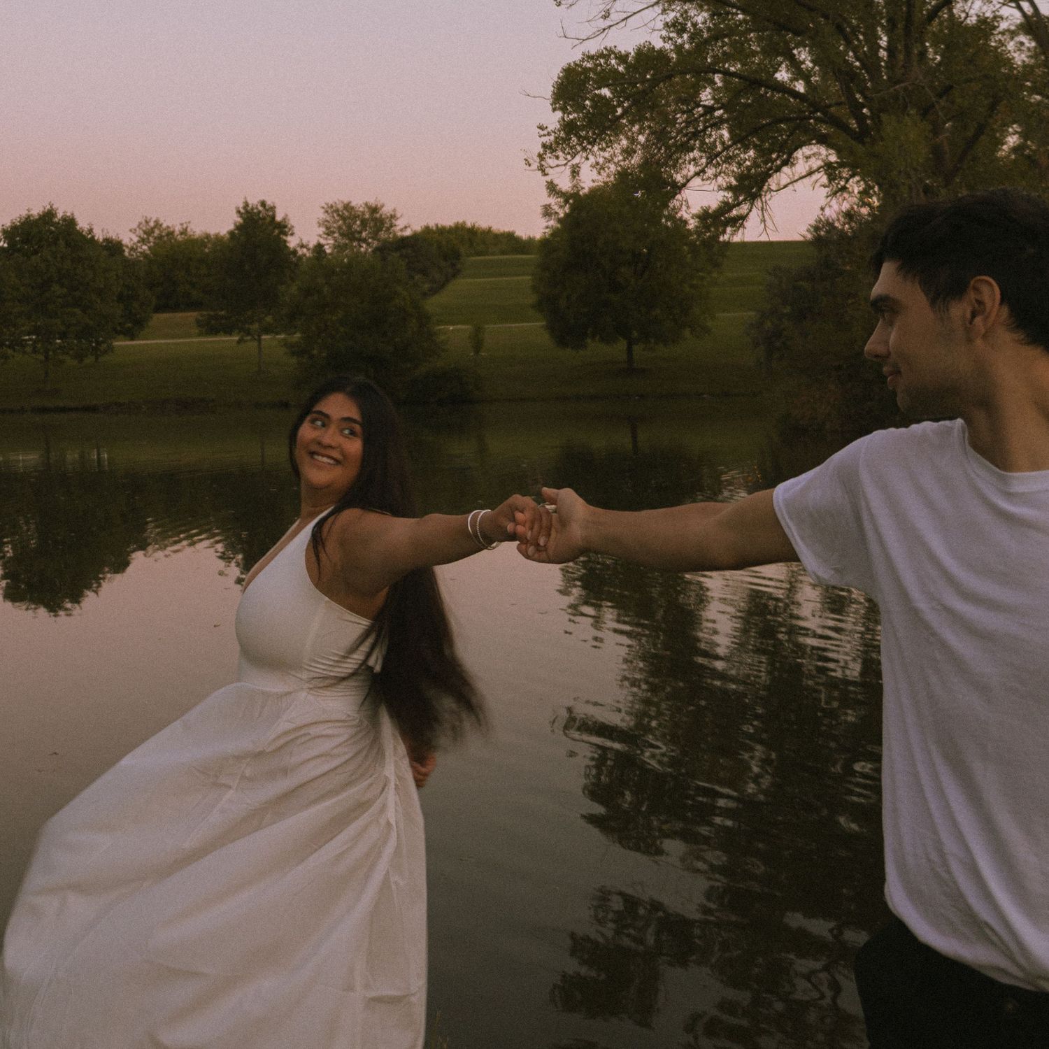 Couple dancing at dusk in front of lake.