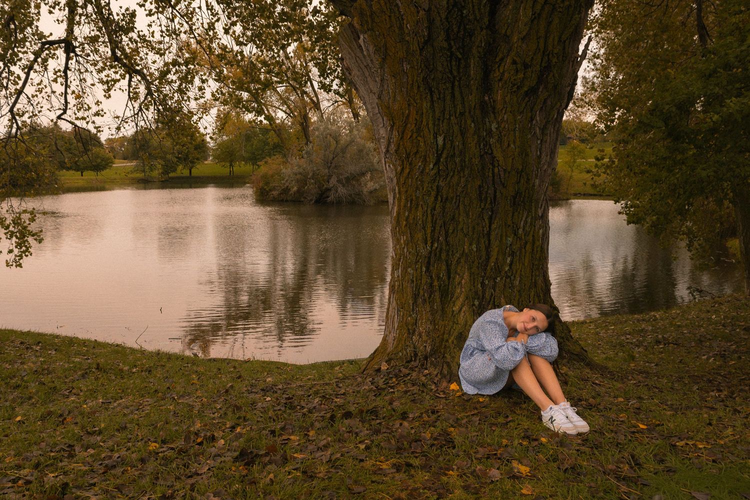 Girl posing in front of tree at lake.