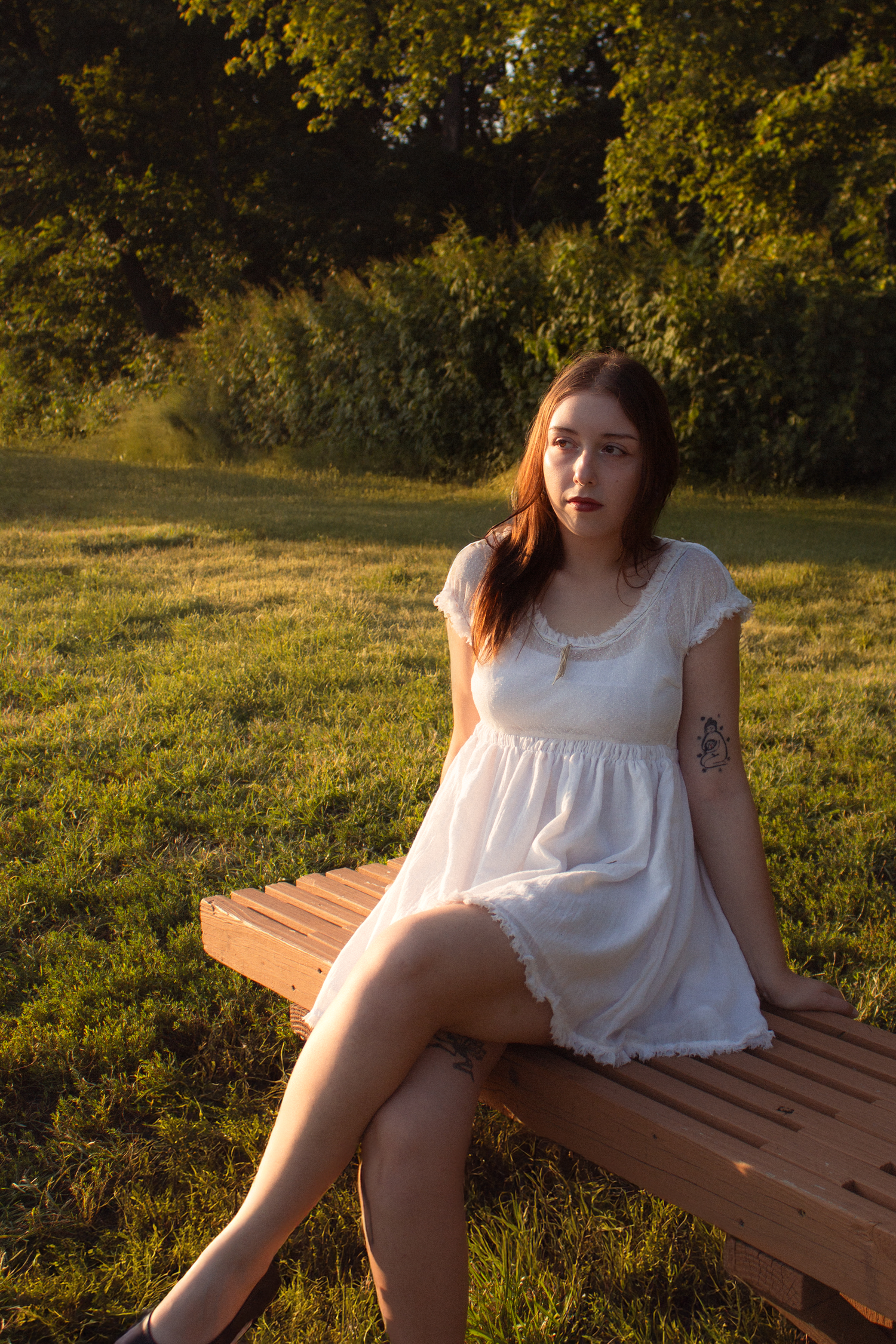 Girl sitting on bench looking off at sunset.
