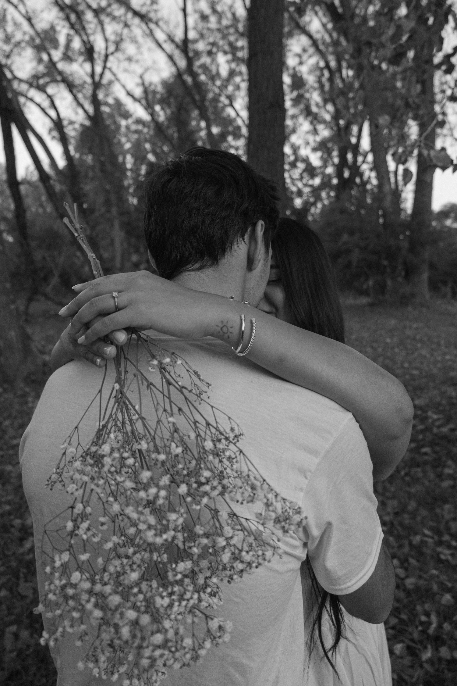Couple hugging and holding flowers in black and white.