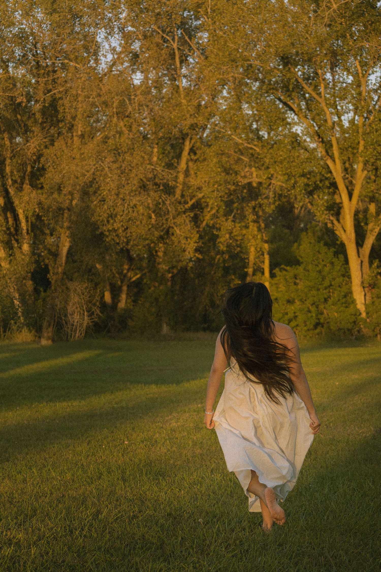 Girl running away in field at sunset.