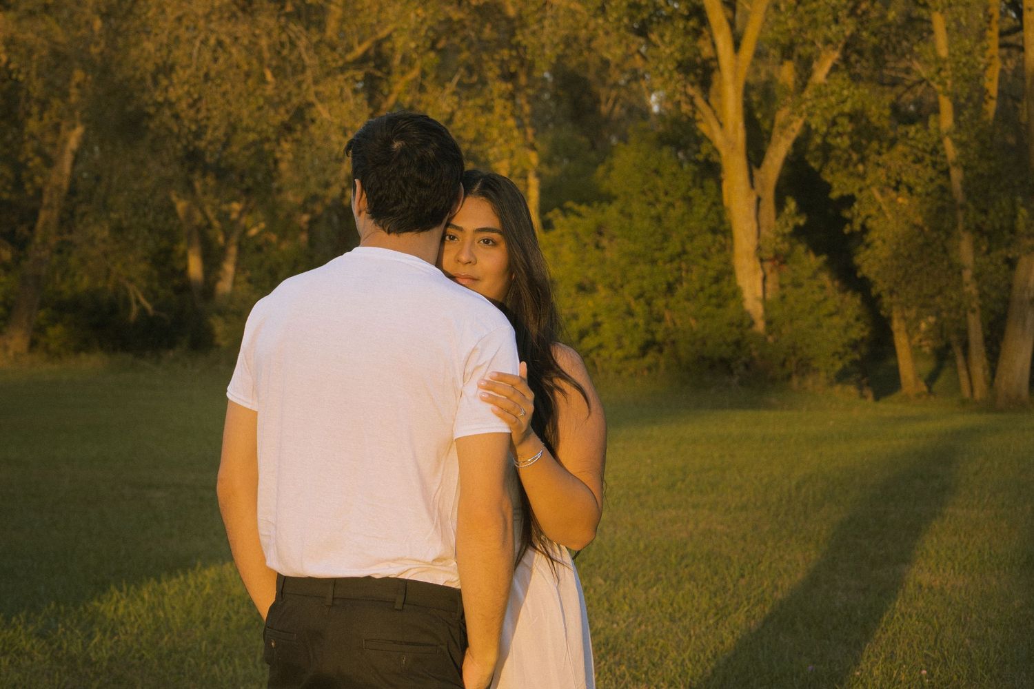 Girl hiding behind boyfriend at sunset.