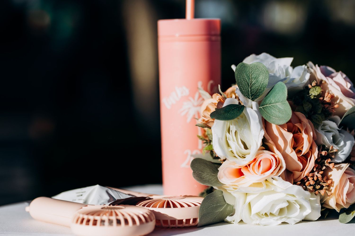 Coral pink candles and floral arrangements with eucalyptus leaves on a wedding table.